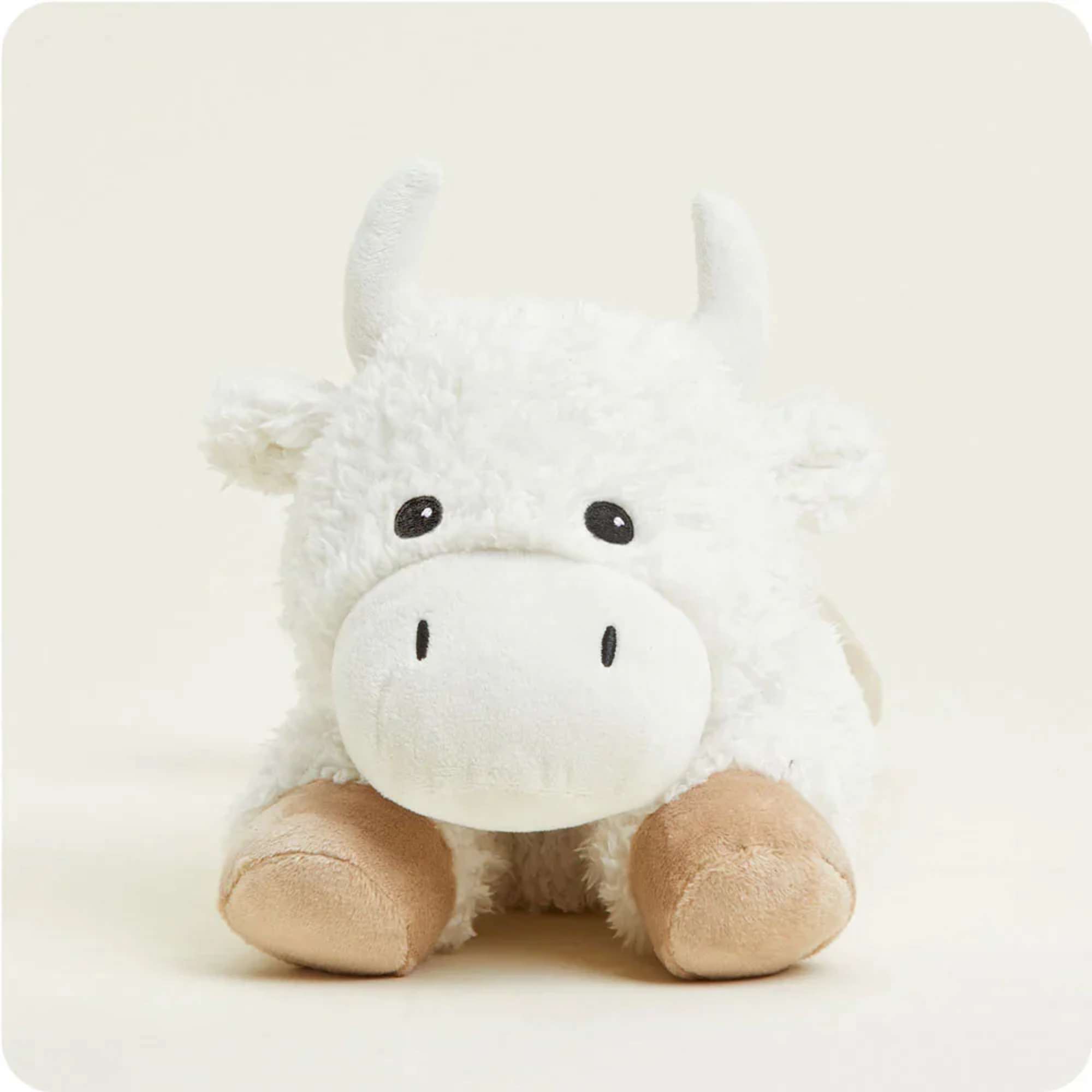 White plush cow toy with tan hooves on a plain background