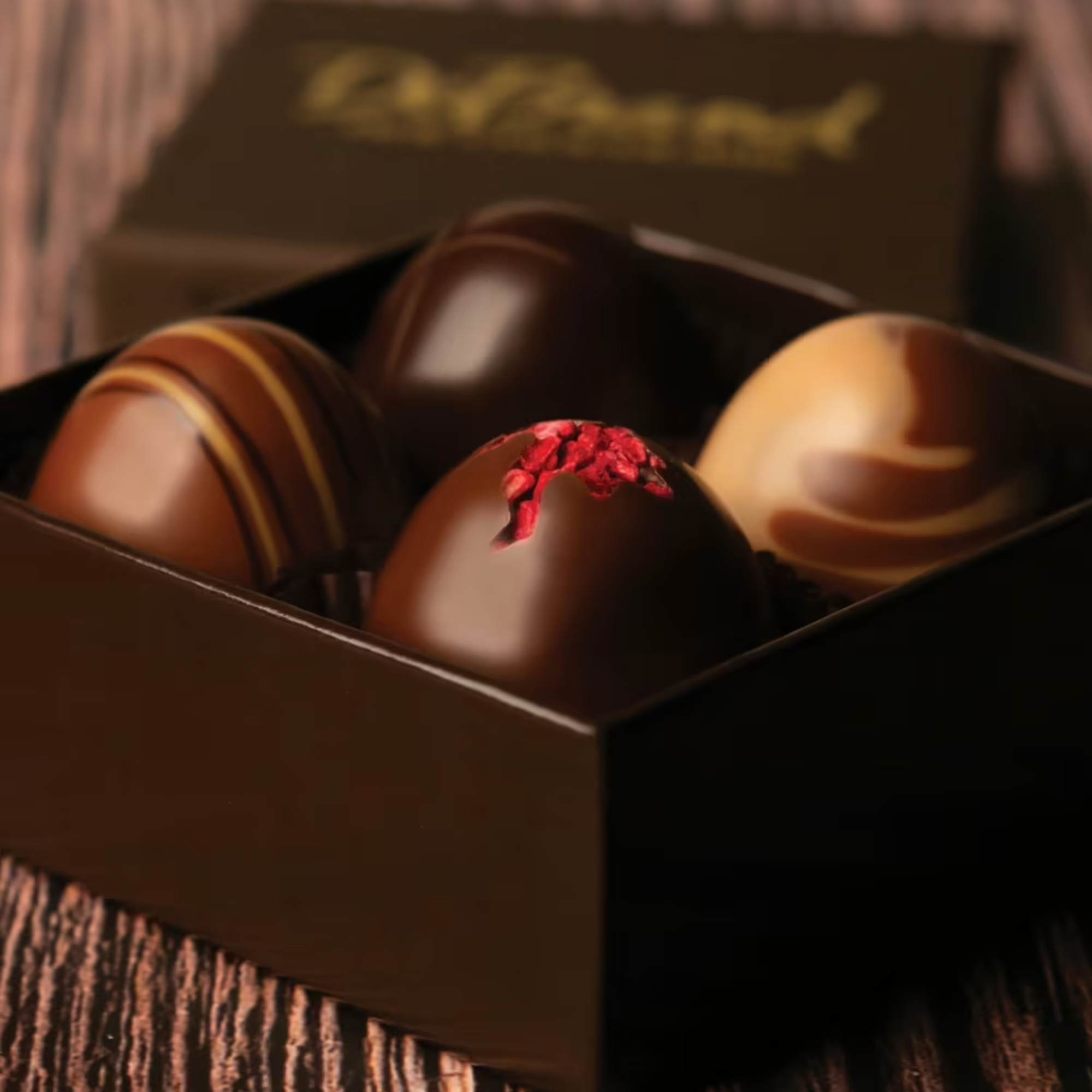 Box of assorted chocolate truffles on a wooden surface