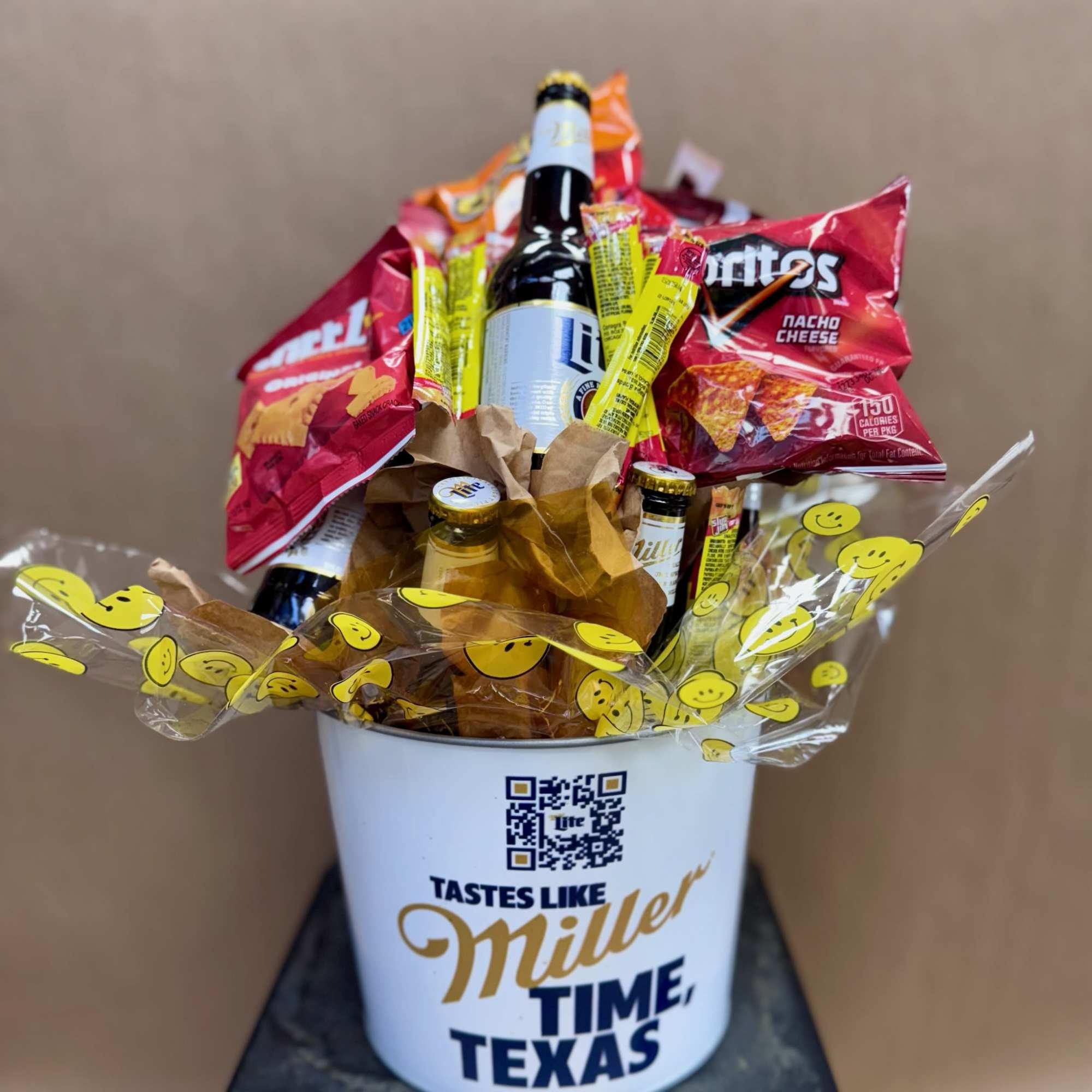 Beer and snacks arranged in a white bucket with smiley-print wrap