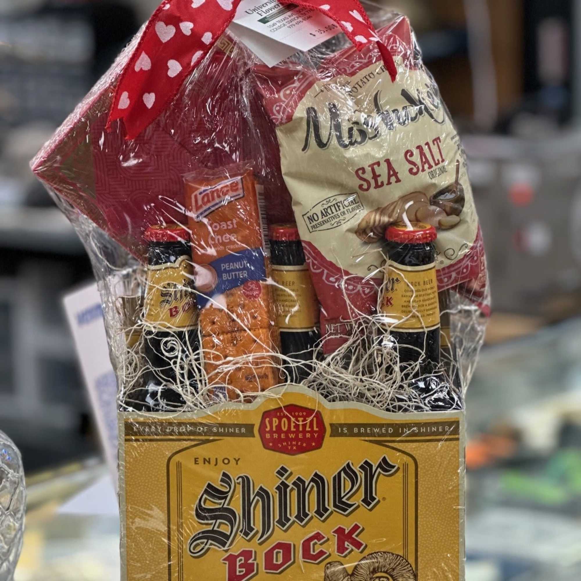 Gift basket with beer bottles, snacks, and a bag of chips wrapped in cellophane