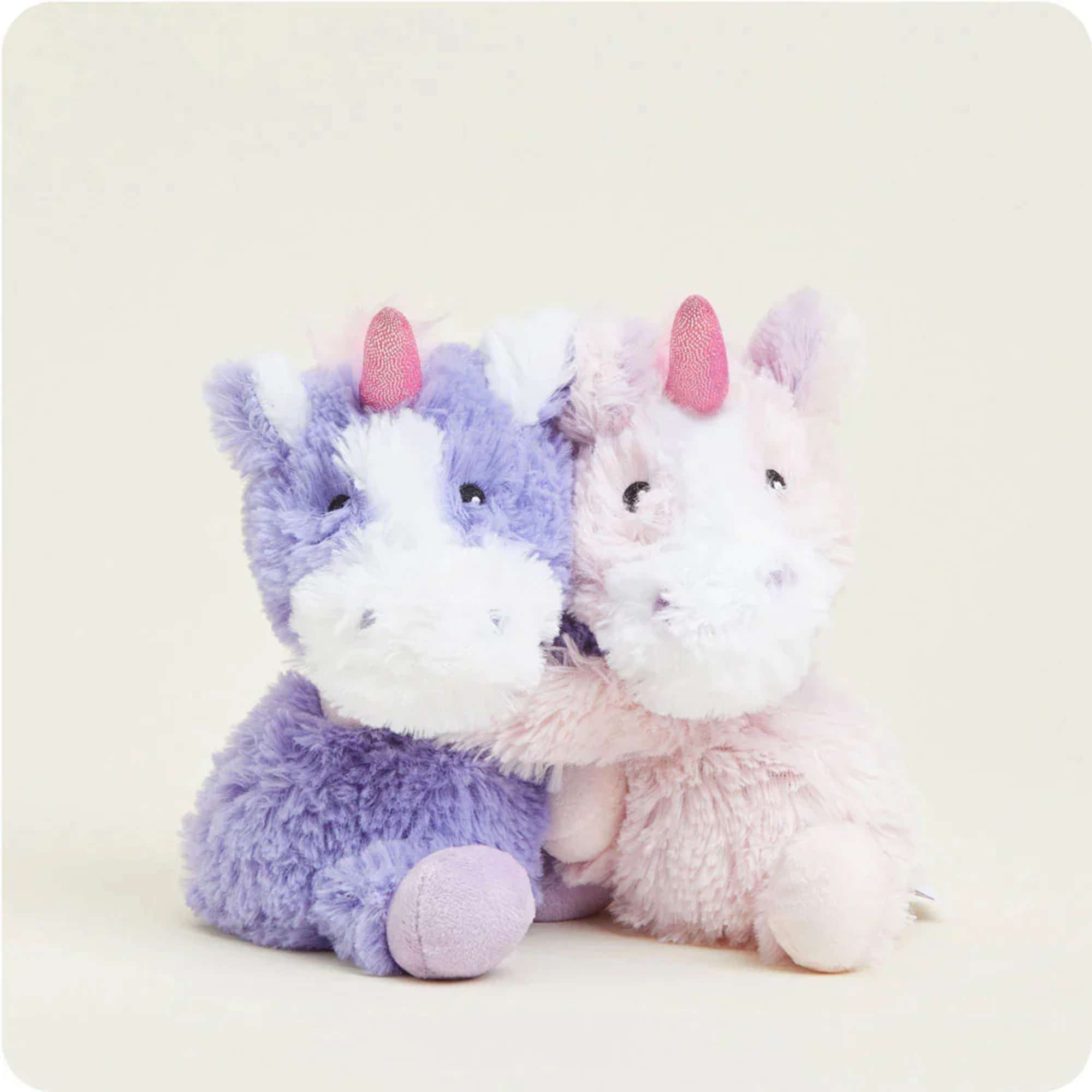 Two plush unicorn toys, one lavender and one pink, sitting side by side