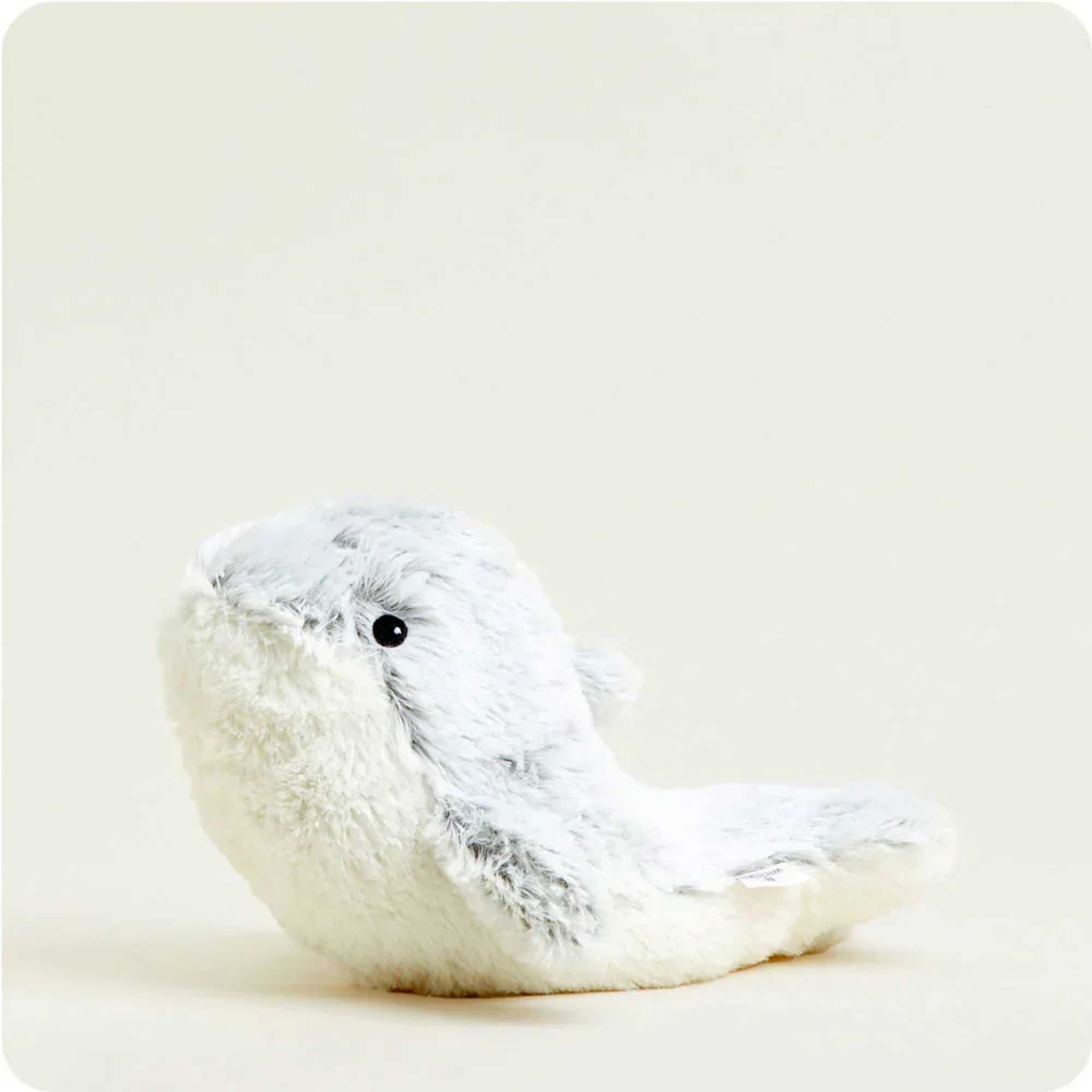 Small white plush bird with a black eye on a plain background