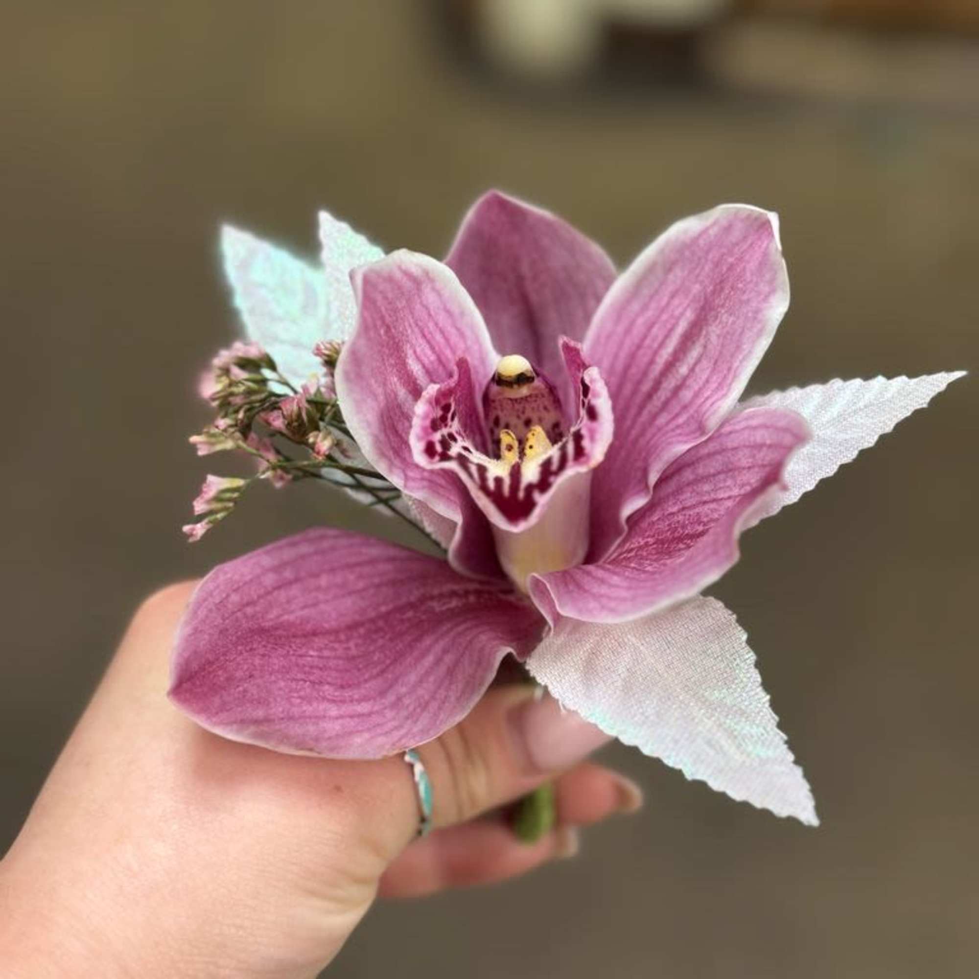 Handheld pink orchid corsage with white fabric leaves