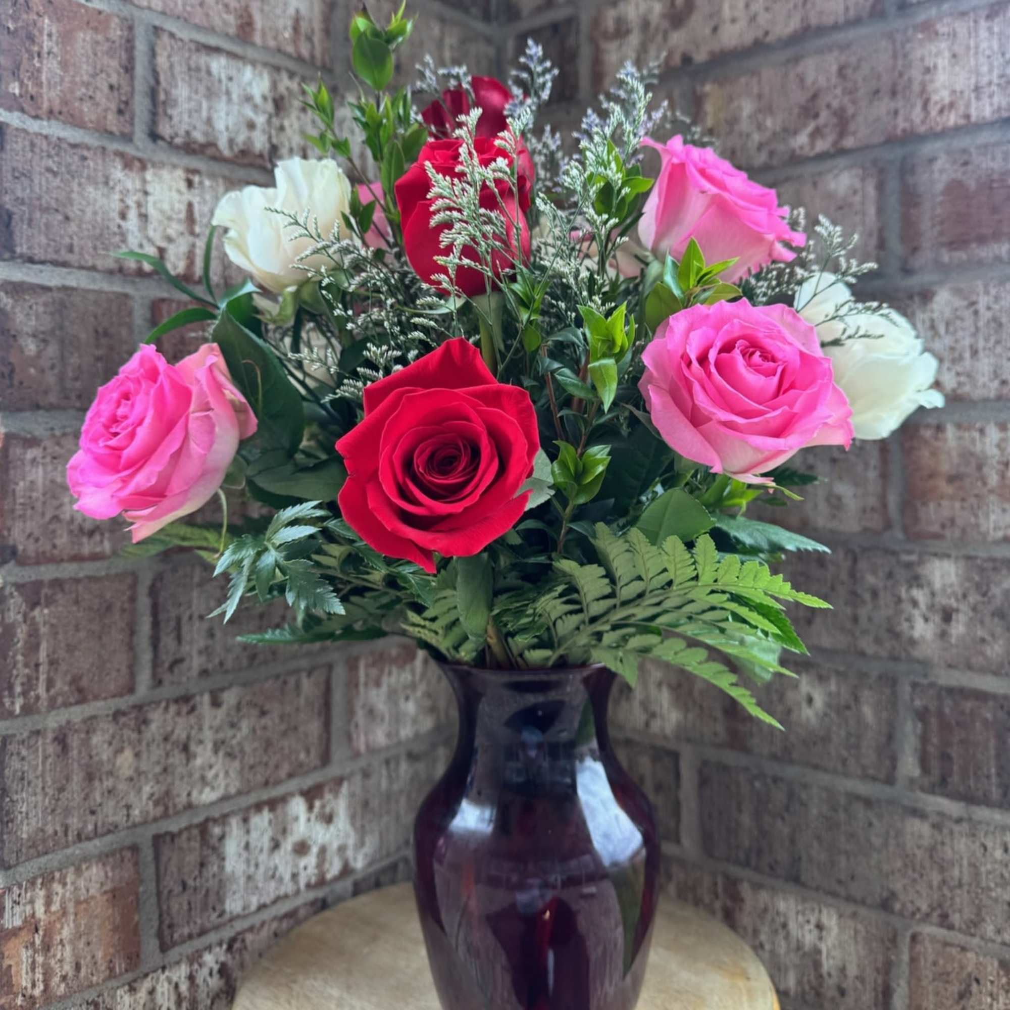 Pink, red, and white roses arranged in a dark glass vase