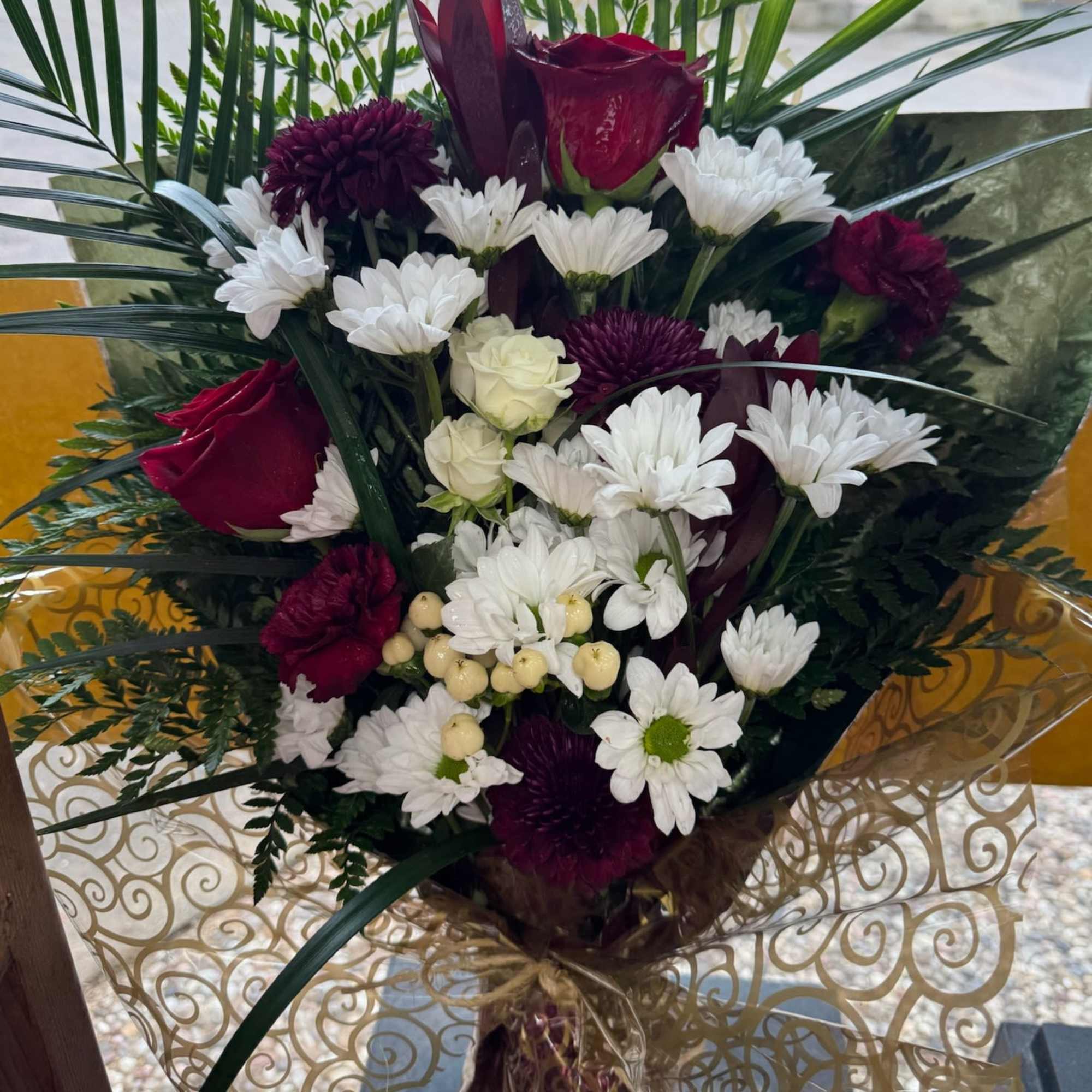 Bouquet of red roses and white daisies with dark purple blooms