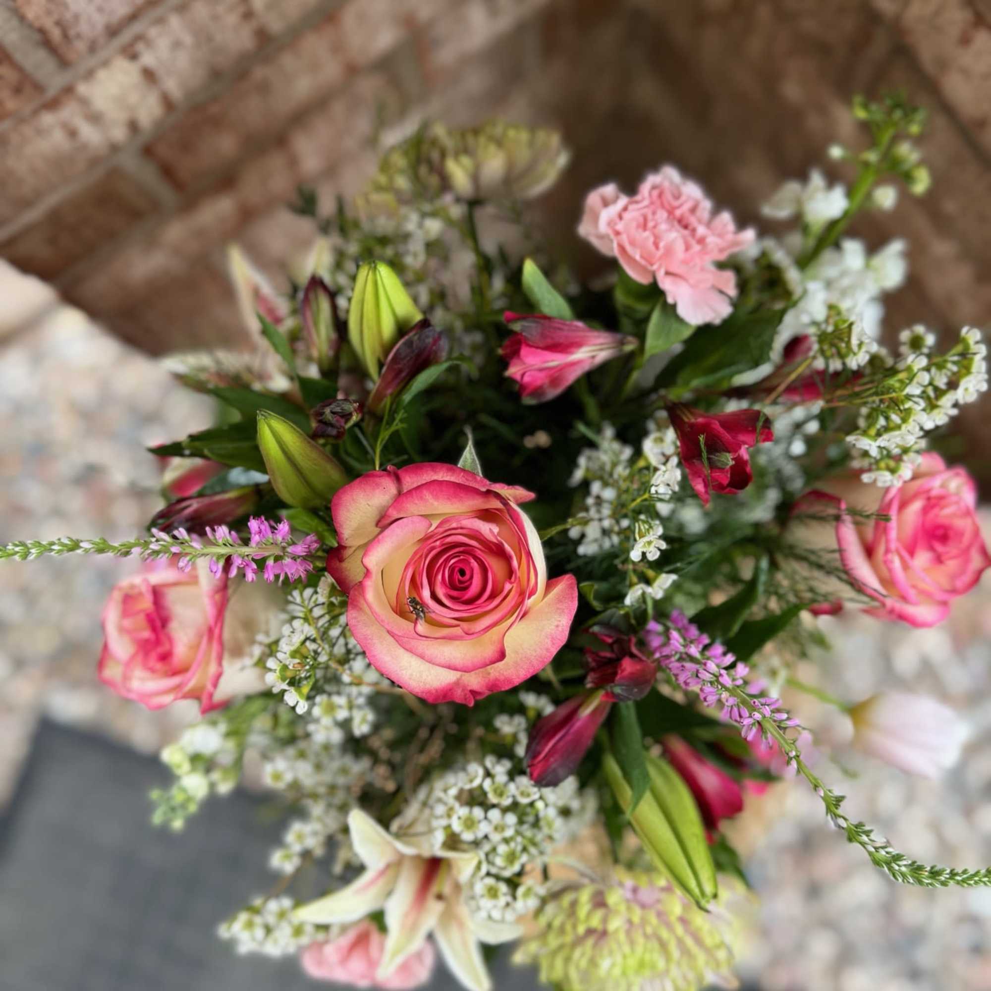 Bouquet of pink roses, lilies, and carnations with white filler flowers