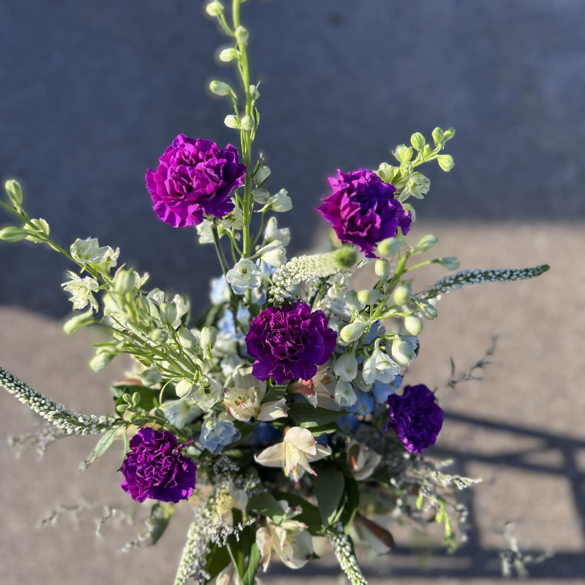 Purple carnations with white and blue mixed flowers in a loose bouquet