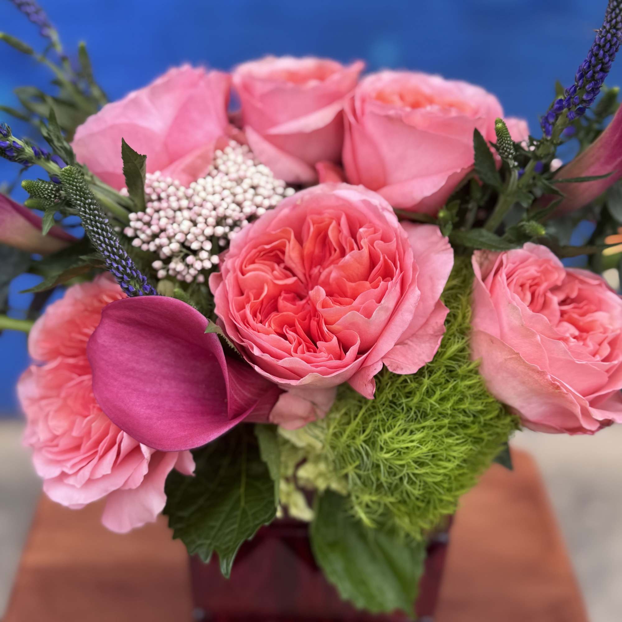 Pink roses and a magenta calla lily in a square vase