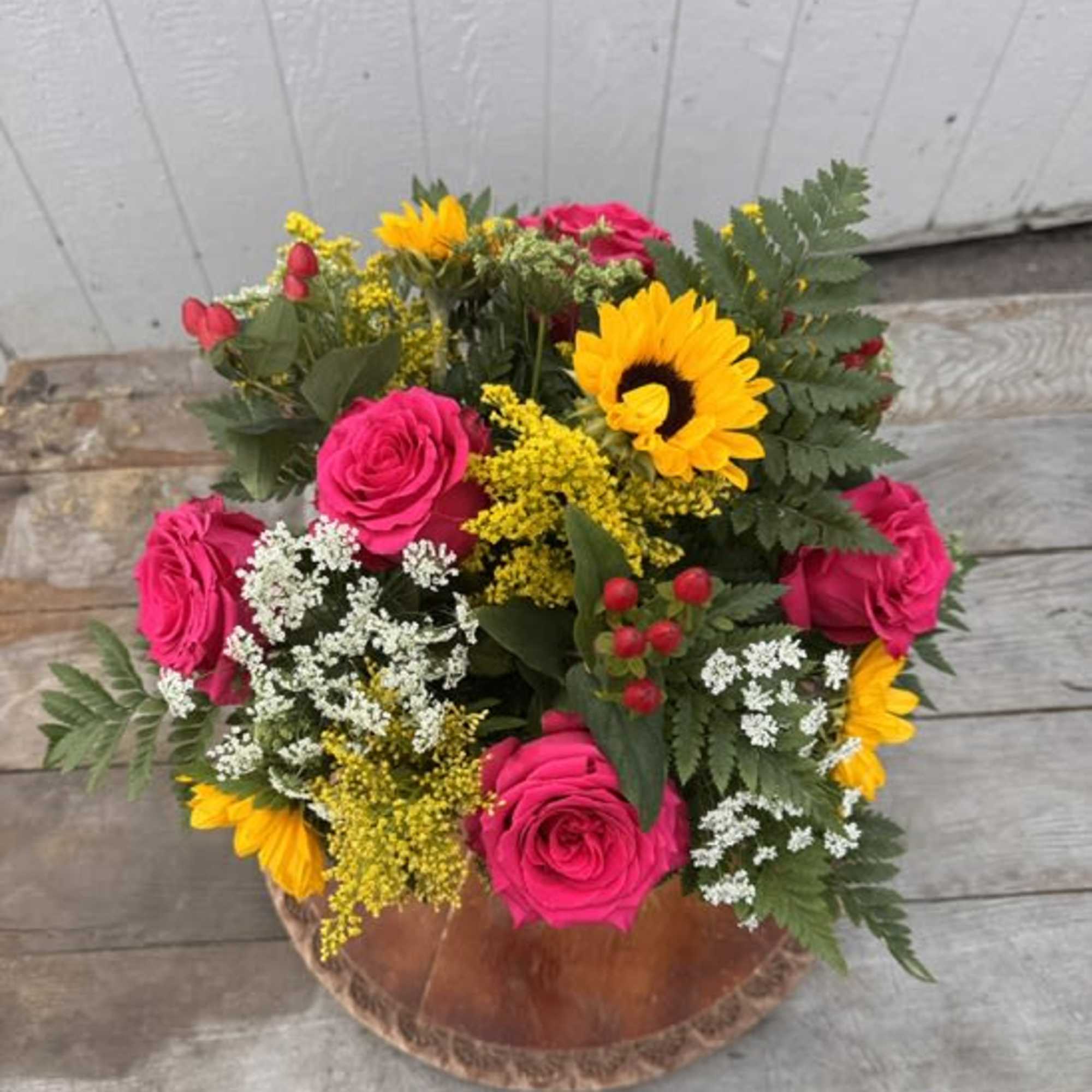 Bouquet of hot pink roses and yellow sunflowers in a copper bowl