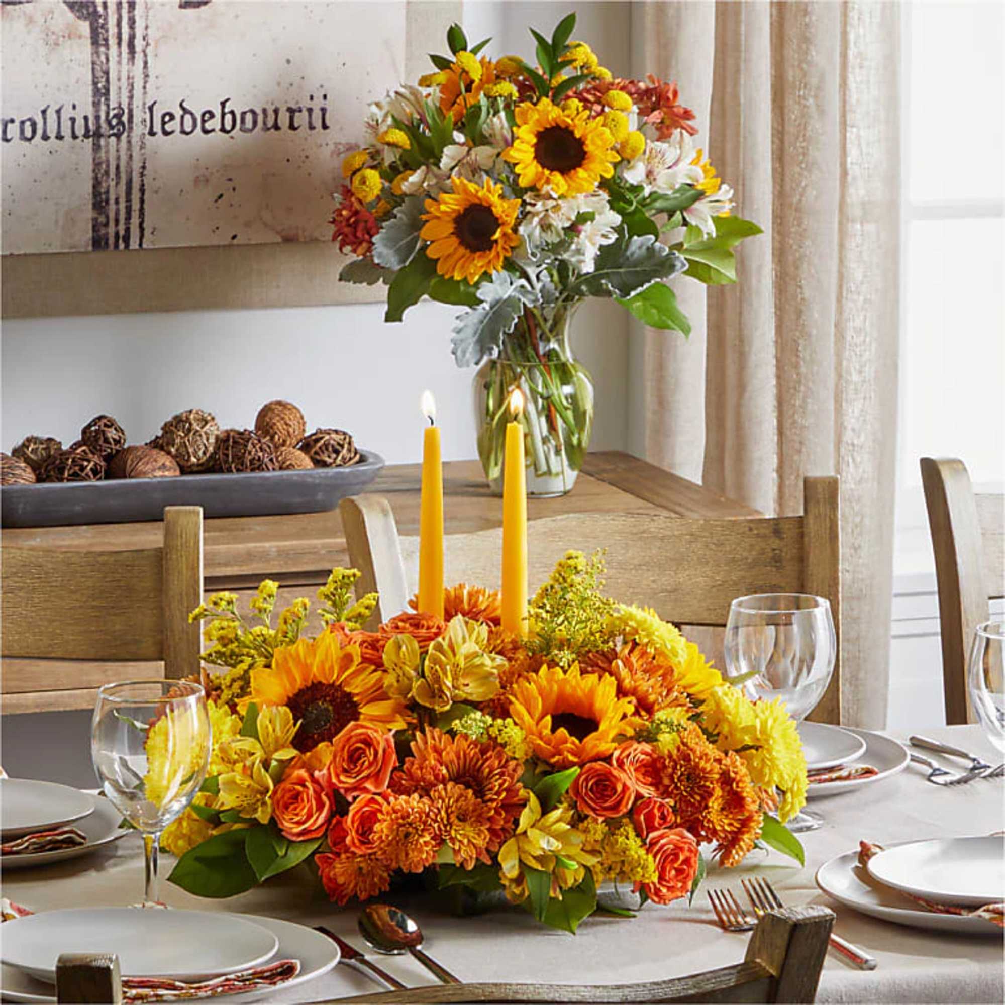 Orange and yellow floral centerpiece with candles on a dining table