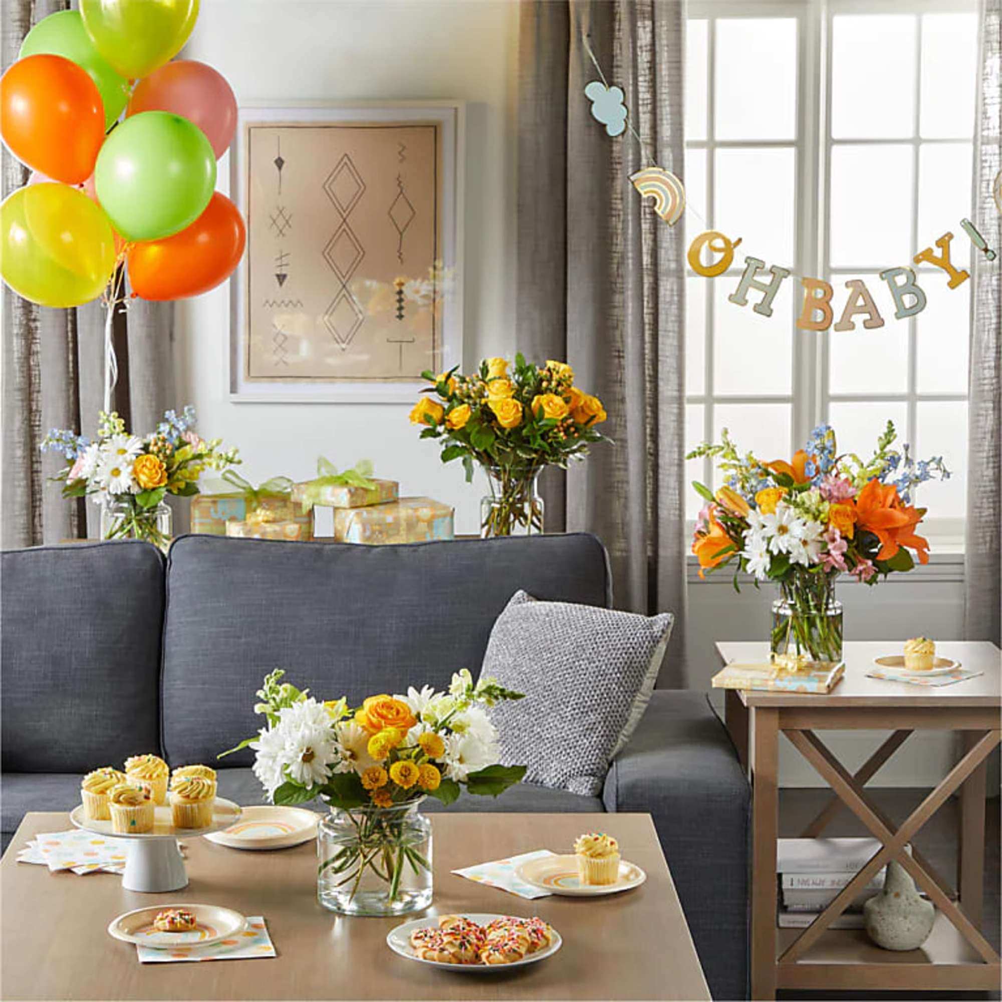 Flower arrangements and balloons in a decorated living room for a baby shower