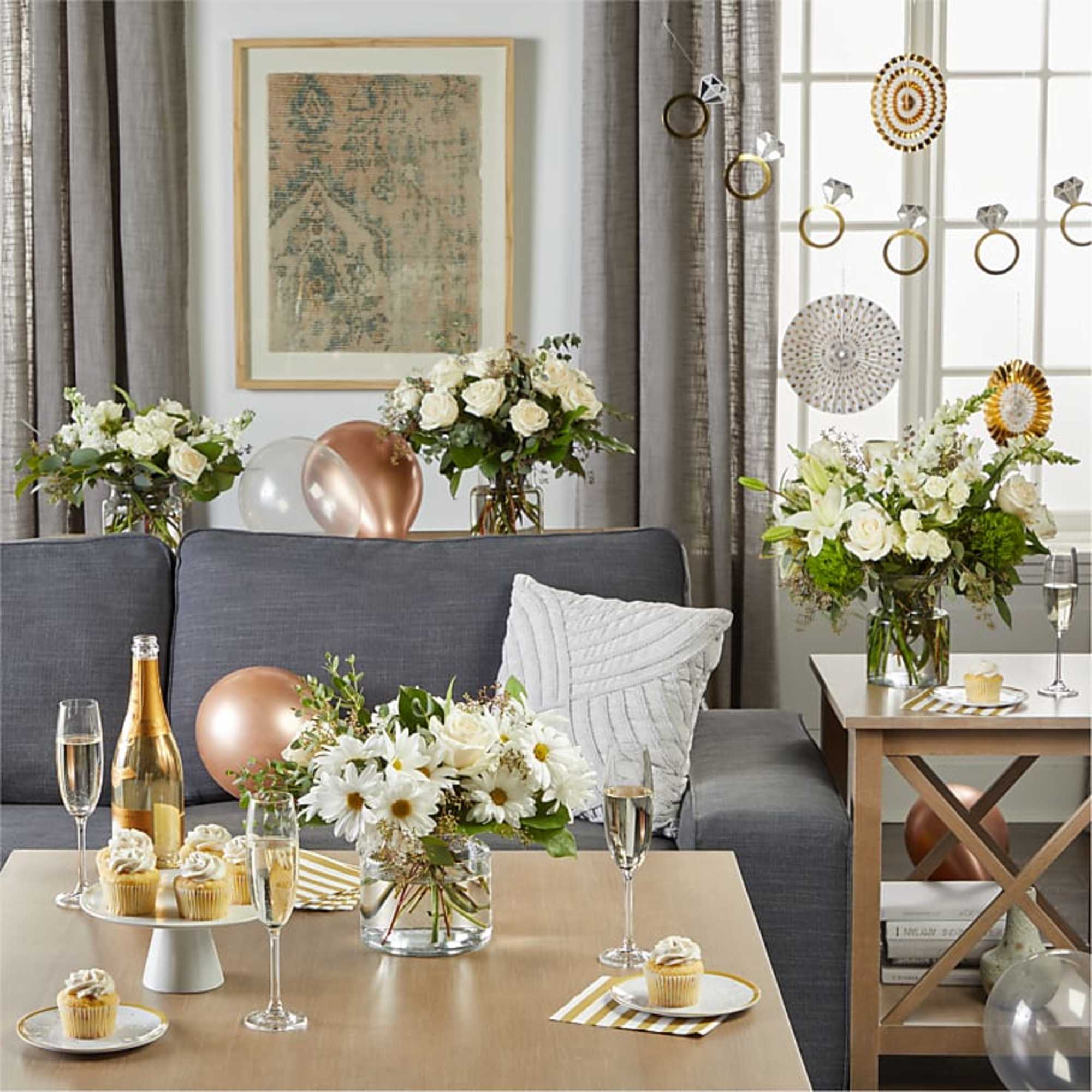 White floral arrangements in glass vases on tables in a decorated living room