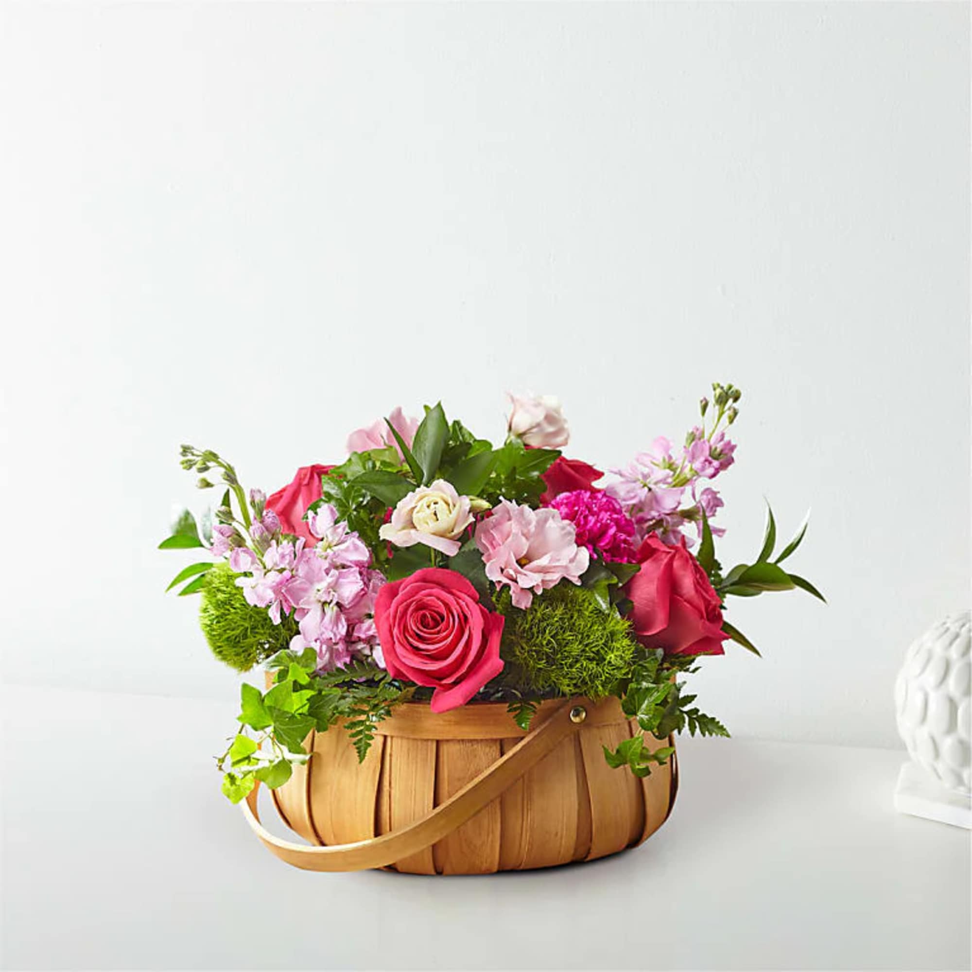 Pink and red flower arrangement in a woven basket