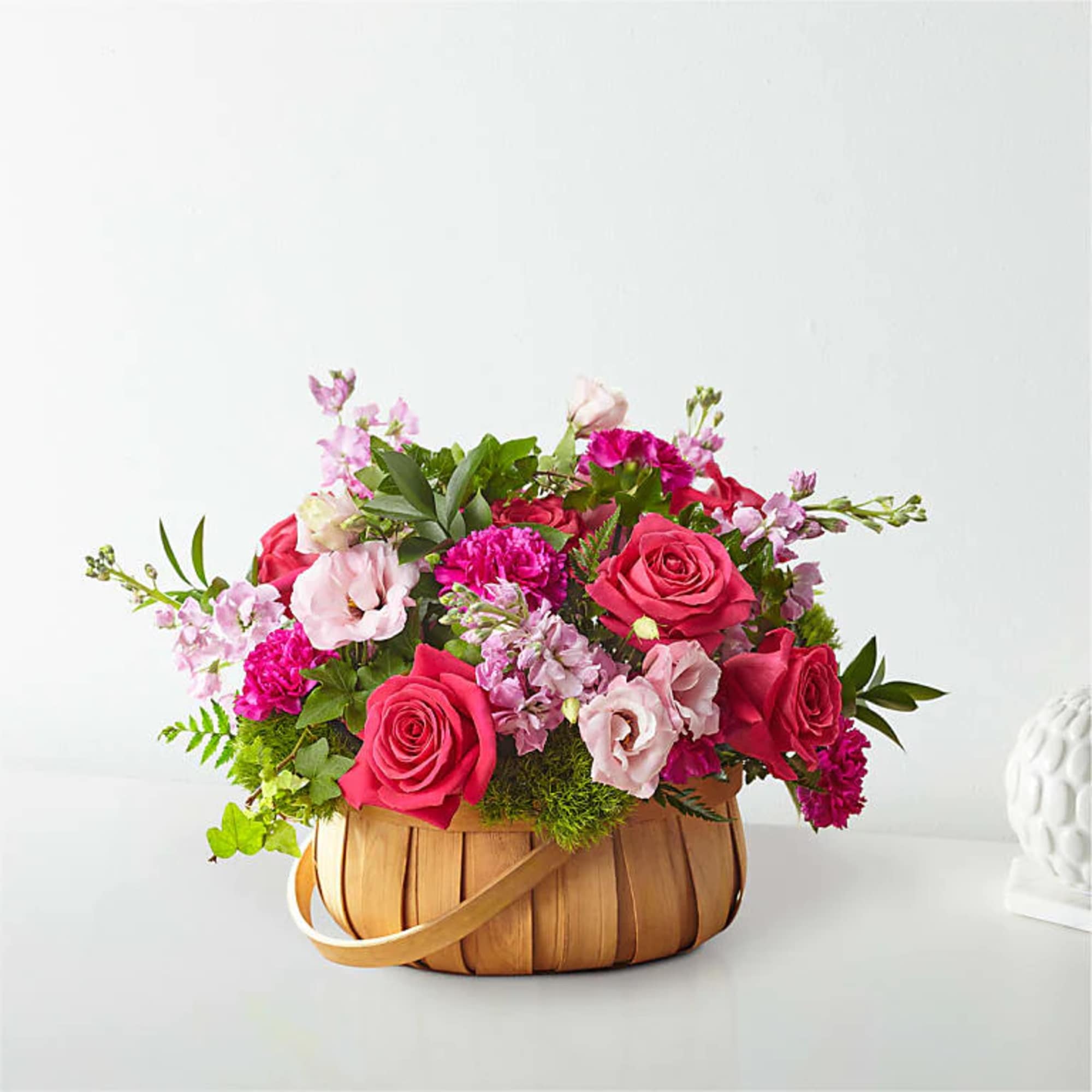 Pink and red flower arrangement in a woven basket