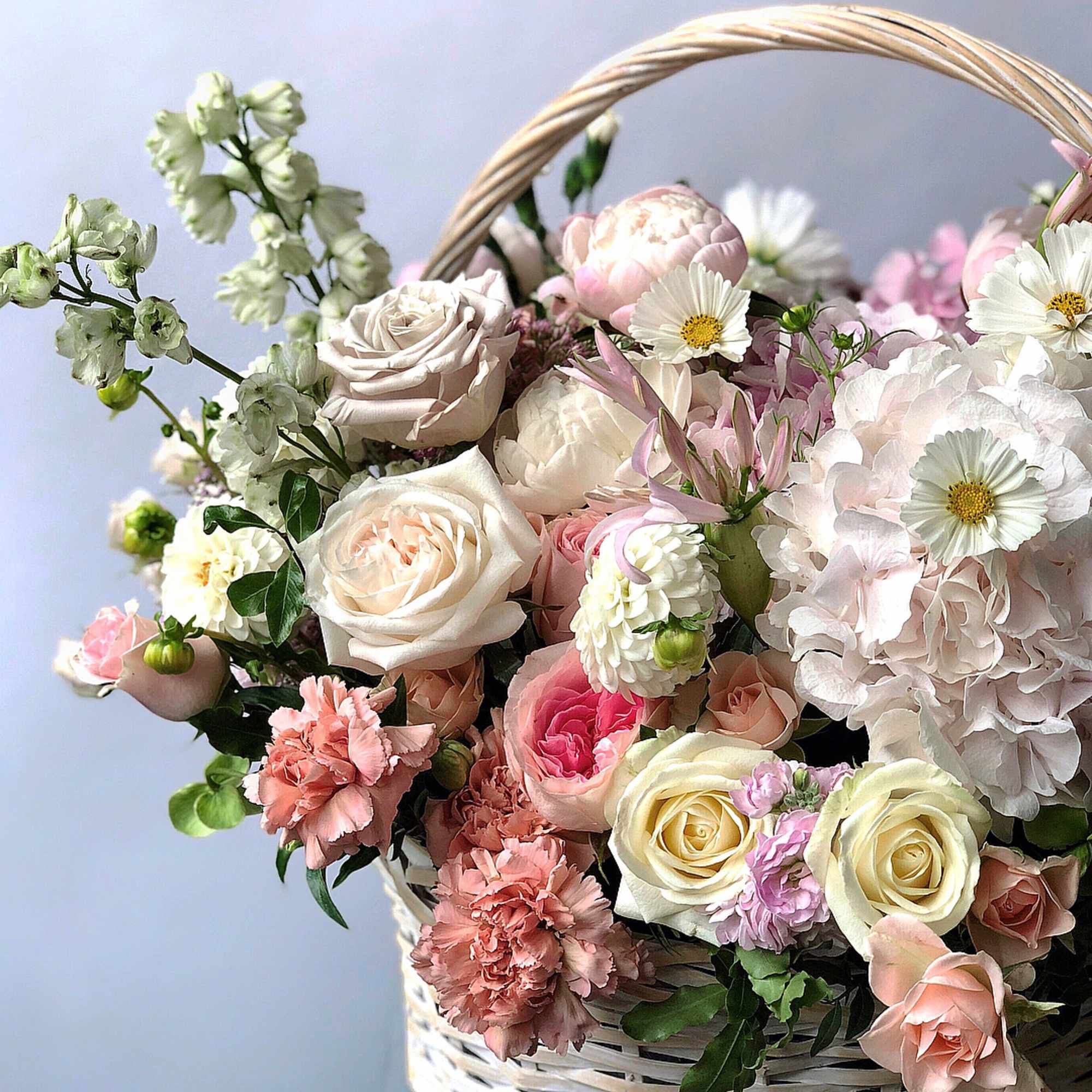 Basket of pastel roses, hydrangea, and daisies