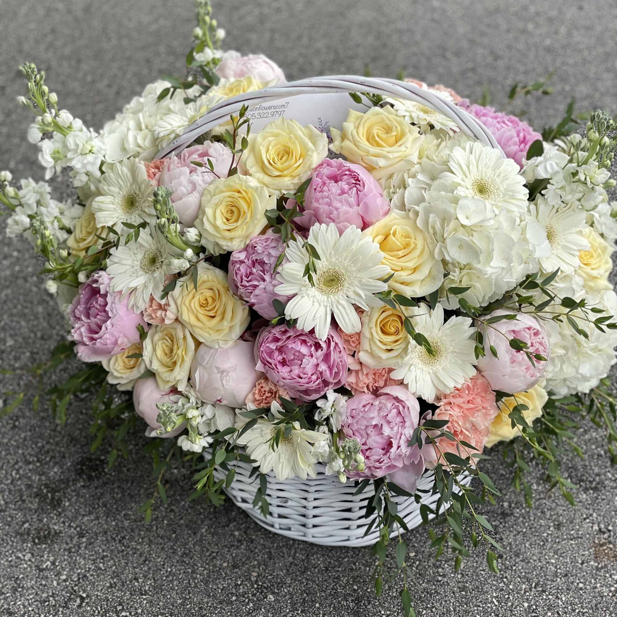 Basket of pastel roses, peonies, and white daisies