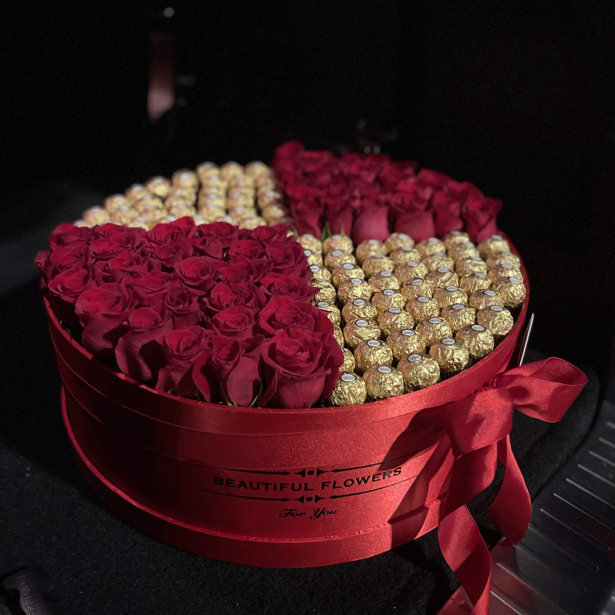 Heart-shaped box of red roses and gold-wrapped chocolates with a red ribbon