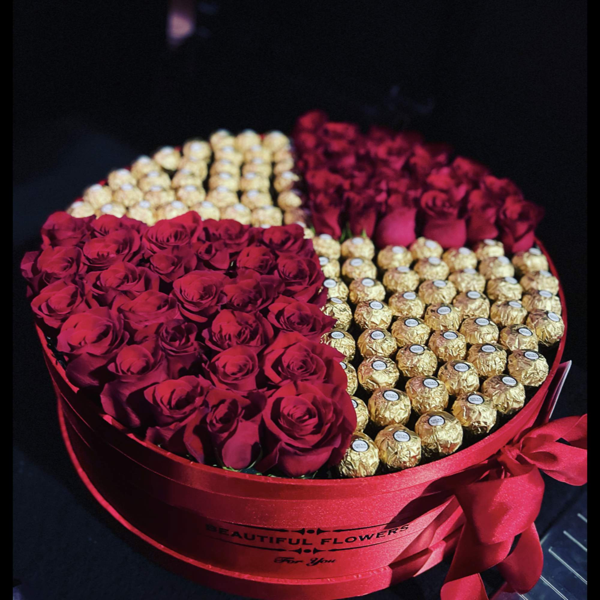 Heart-shaped box of red roses and gold-wrapped chocolates with a red ribbon