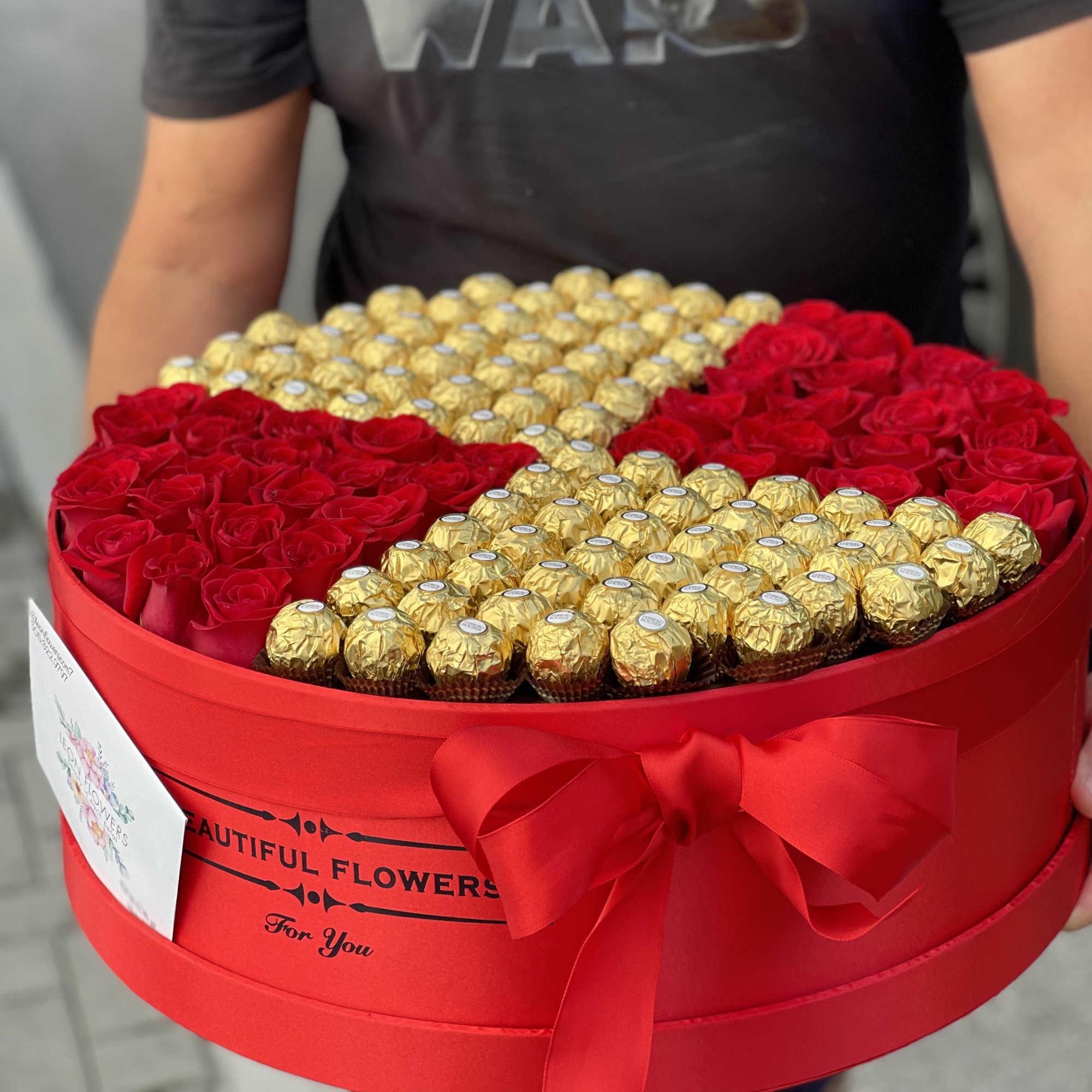 Heart-shaped box of red roses and gold-wrapped chocolates with a red bow