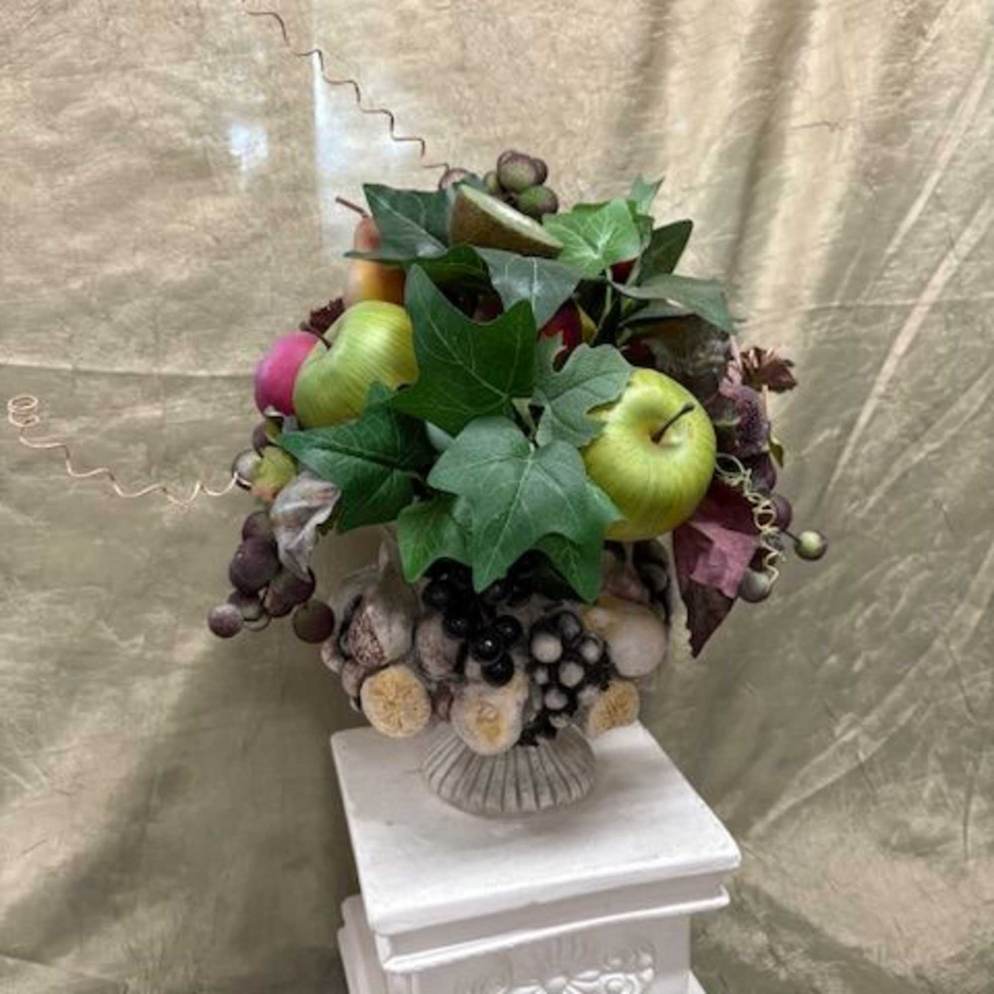 Fruit arrangement with apples and grapes in a decorative vase
