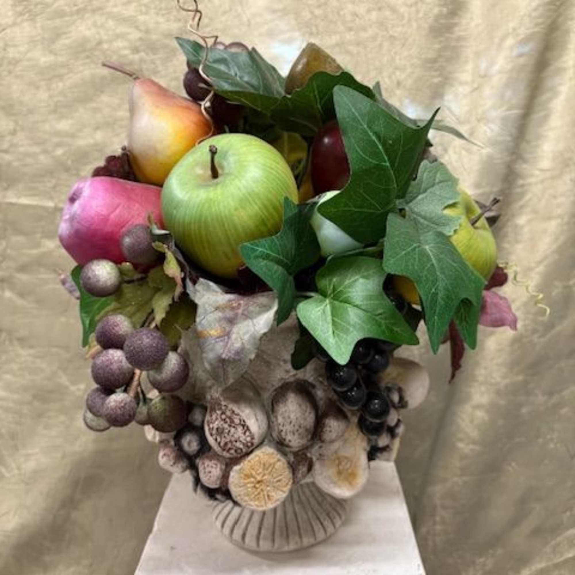Fruit arrangement with apples, grapes, and ivy in a vase