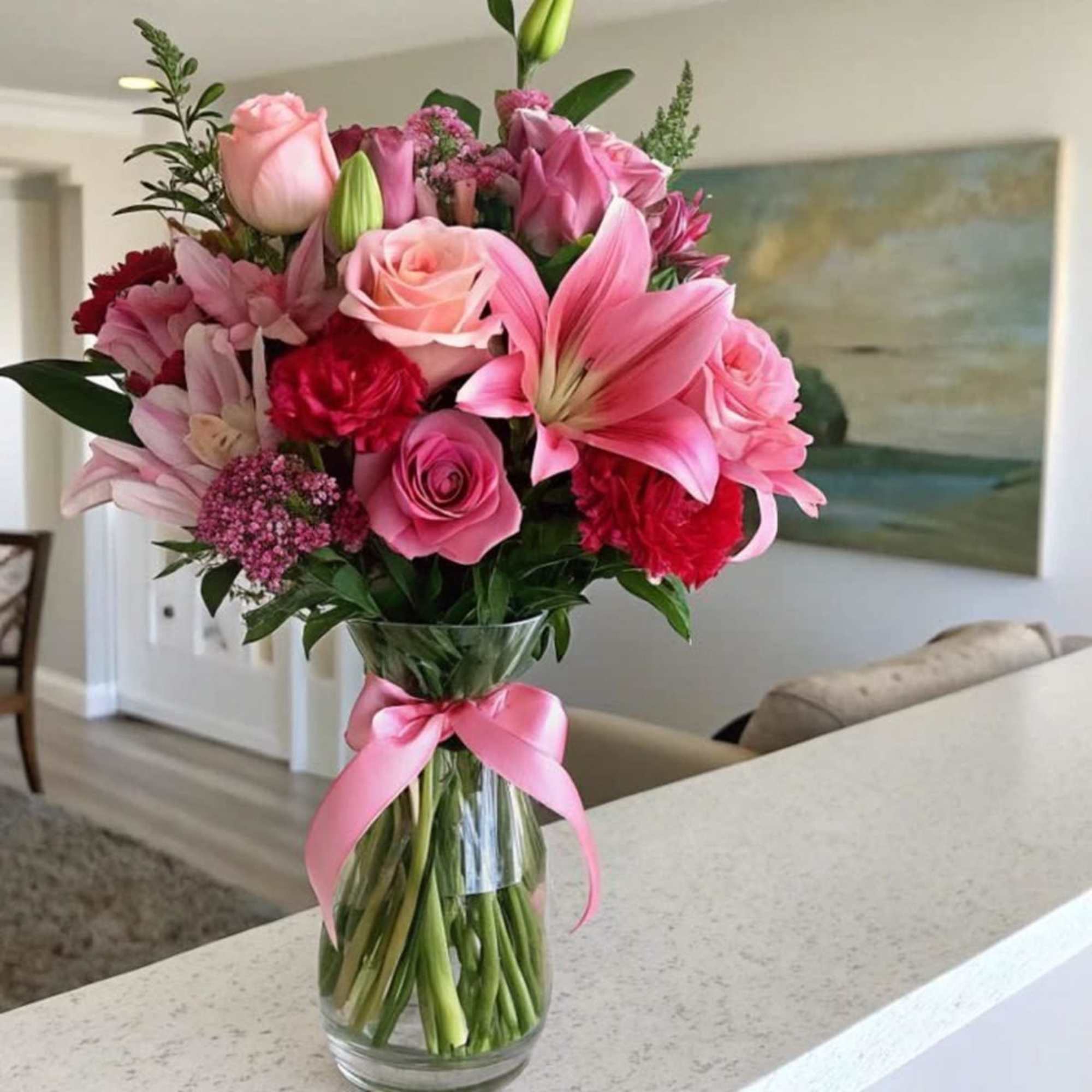 Pink mixed bouquet in a clear glass vase with a pink ribbon