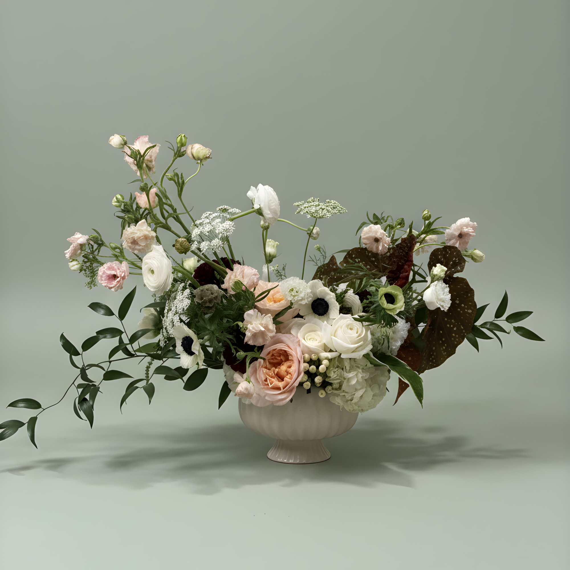 Mixed pastel floral arrangement in a white pedestal vase