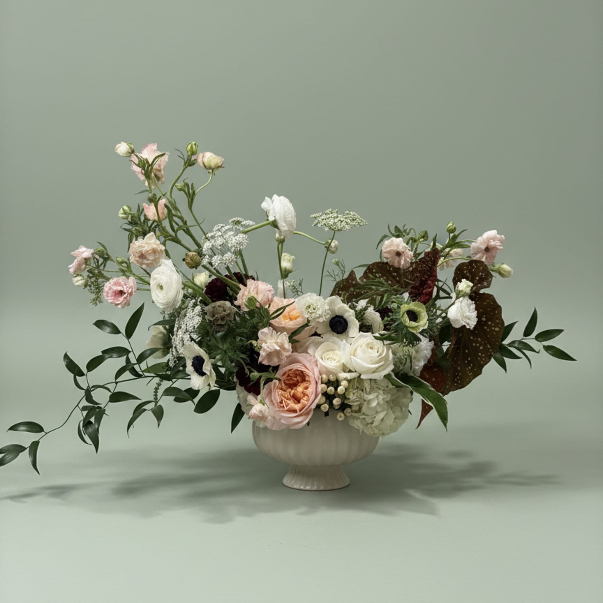 Mixed pastel floral arrangement in a white pedestal vase