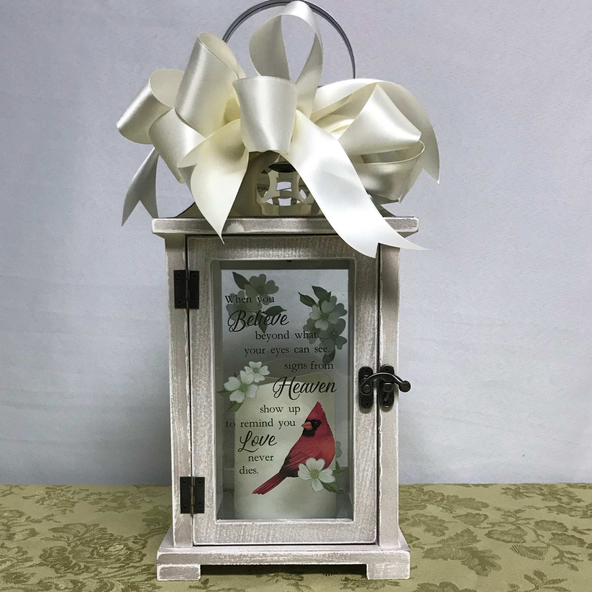 Decorative lantern with a large ivory ribbon bow and a memorial candle inside