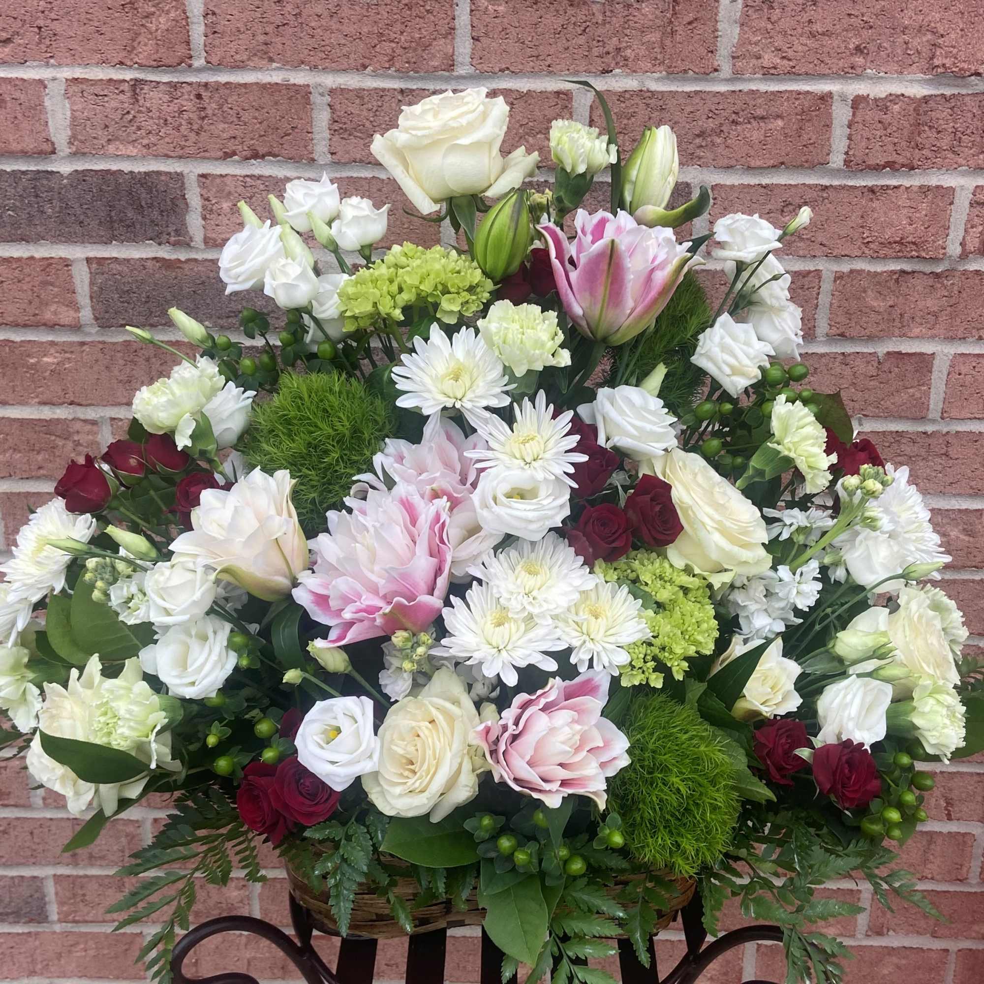 Large mixed floral arrangement with roses, tulips, and white daisies