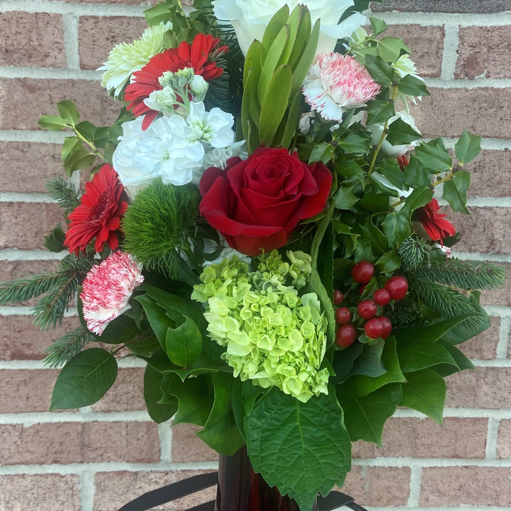 Mixed bouquet in a dark glass vase with red, white, and green flowers