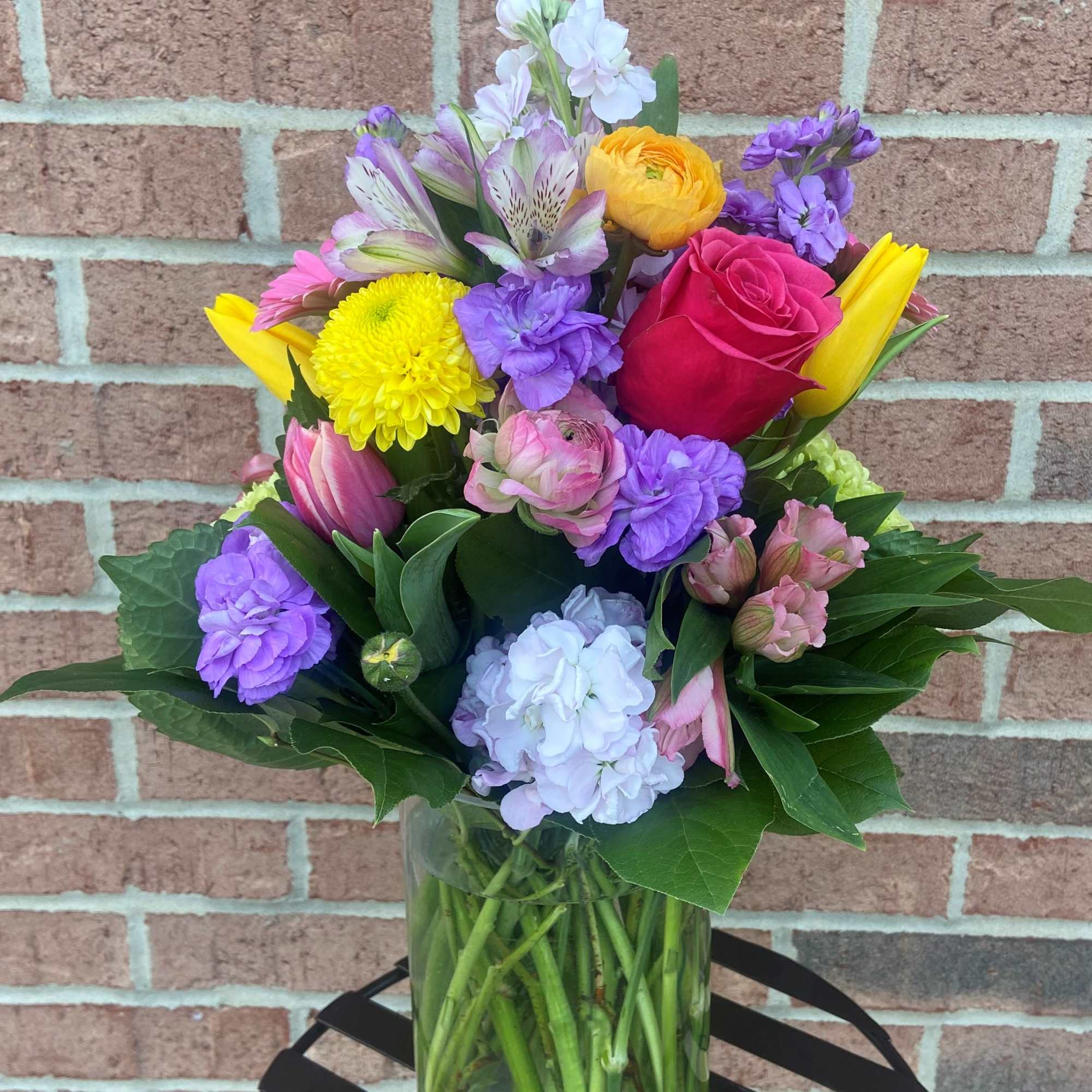 Mixed bouquet of colorful flowers in a clear glass vase