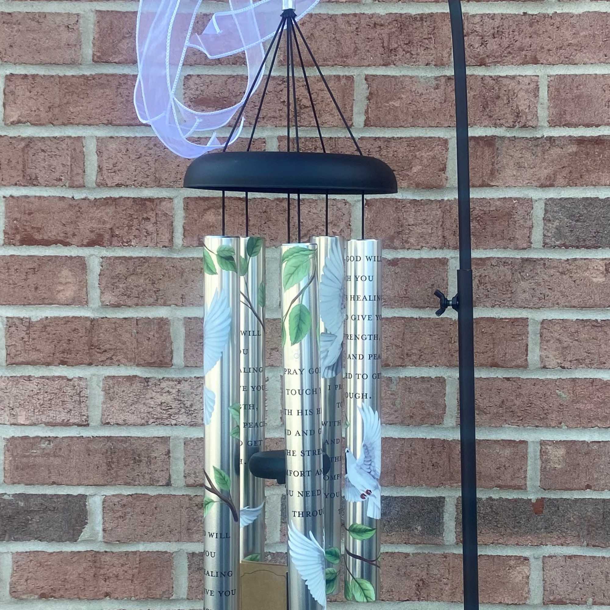 Black metal wind chime with silver tubes and a white ribbon bow