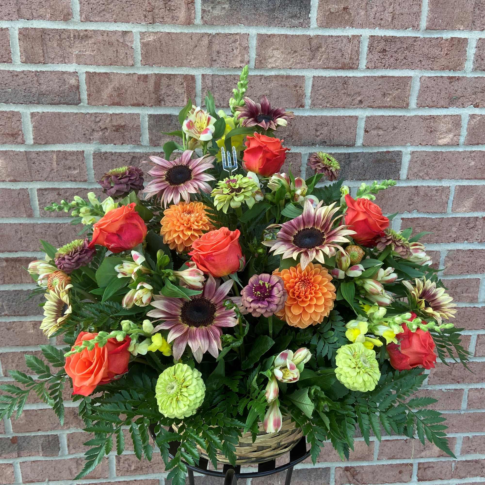 Mixed bouquet of orange roses and colorful daisies in a basket