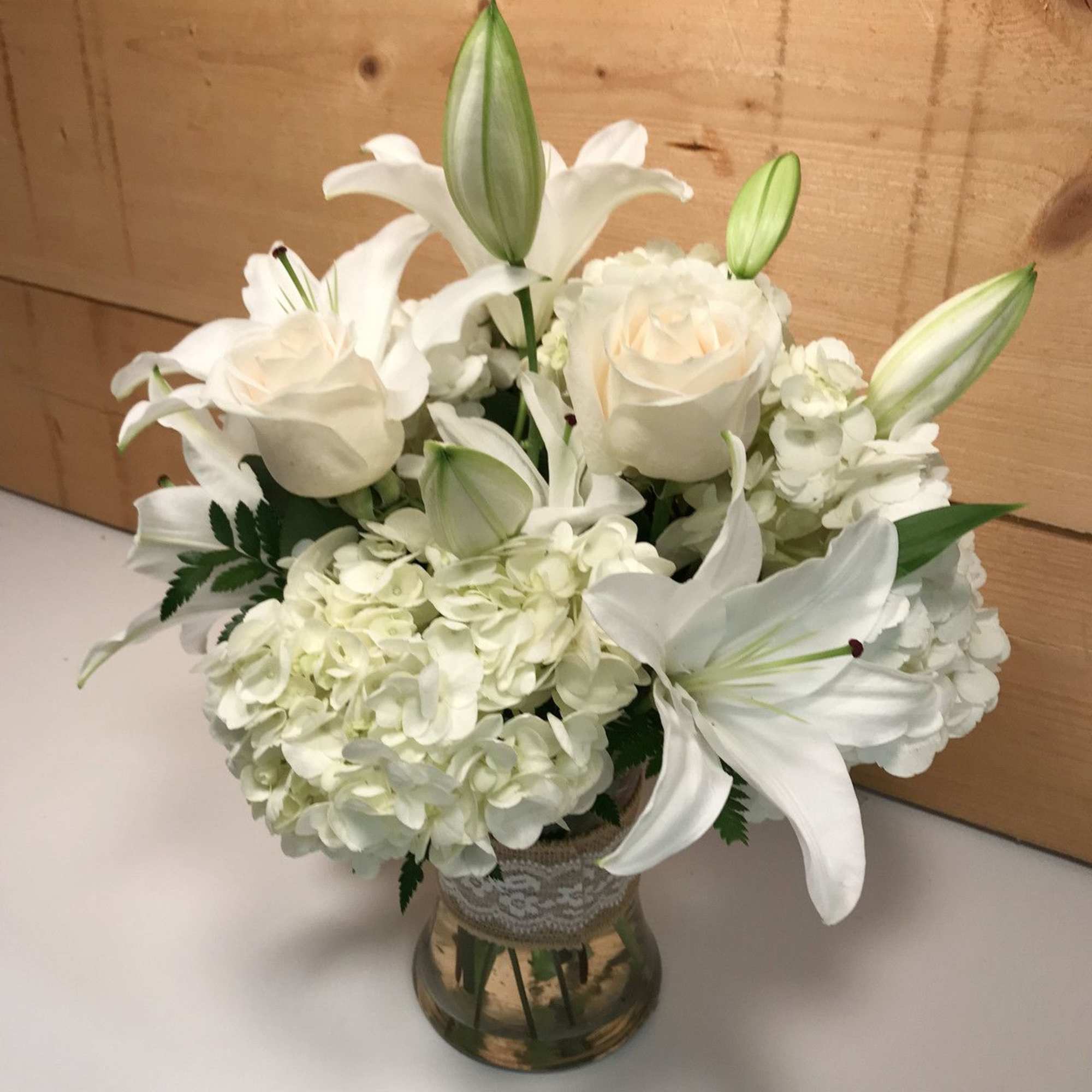White lilies and roses arranged in a glass vase