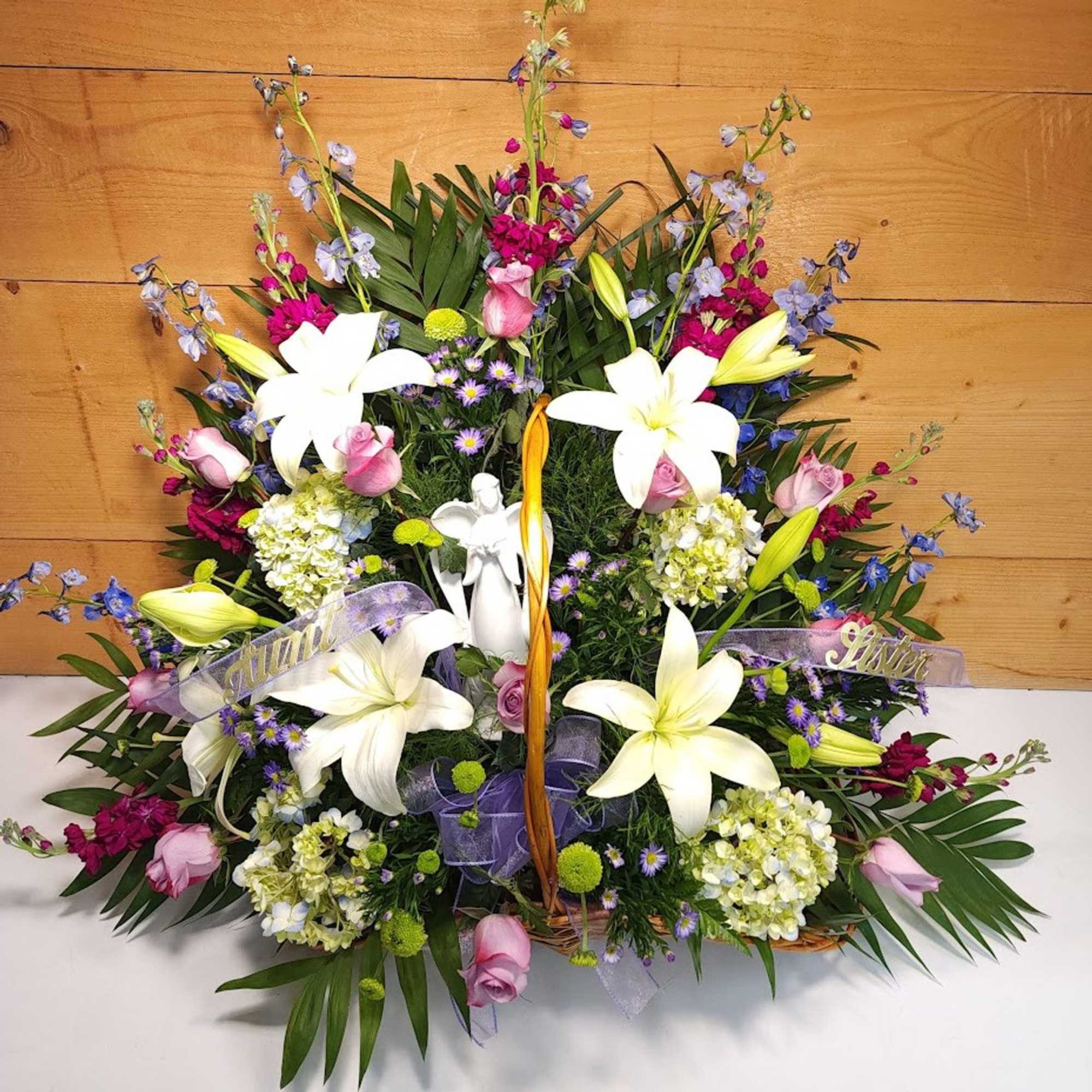 Basket arrangement with white lilies, pink roses, and purple flowers