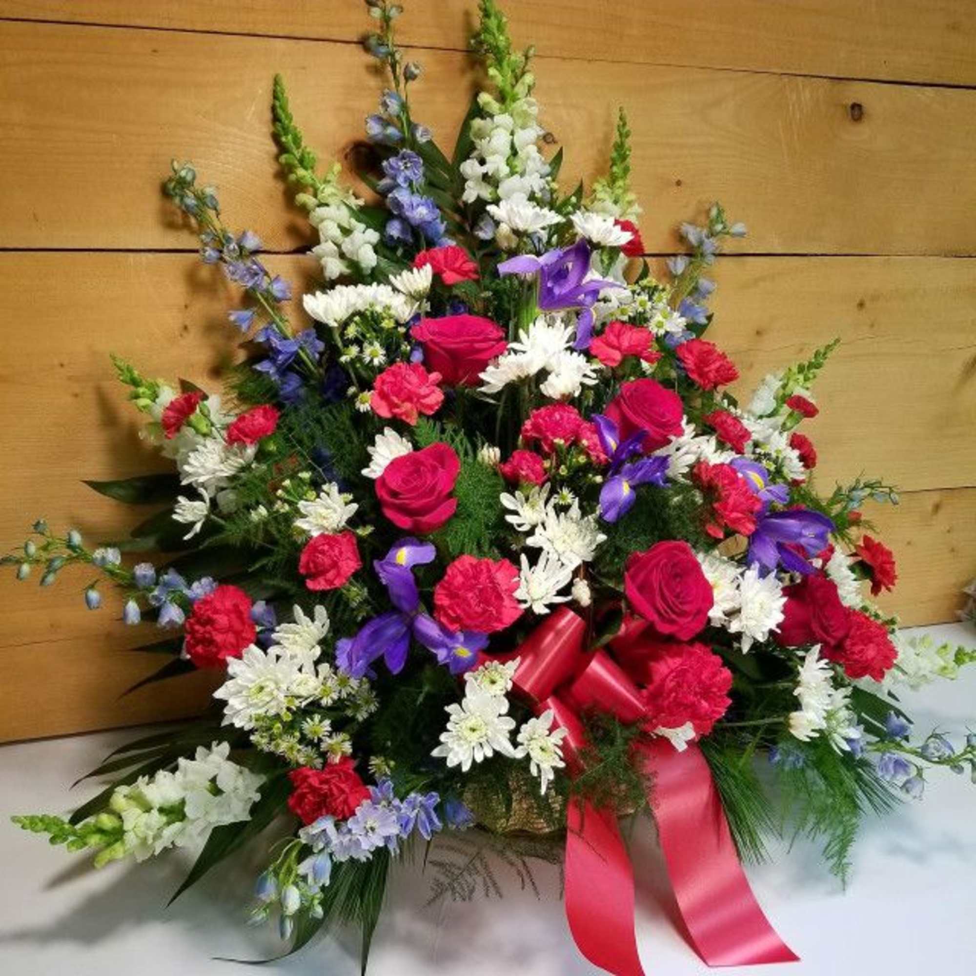 Colorful floral spray with roses, carnations, and daisies tied with a pink ribbon