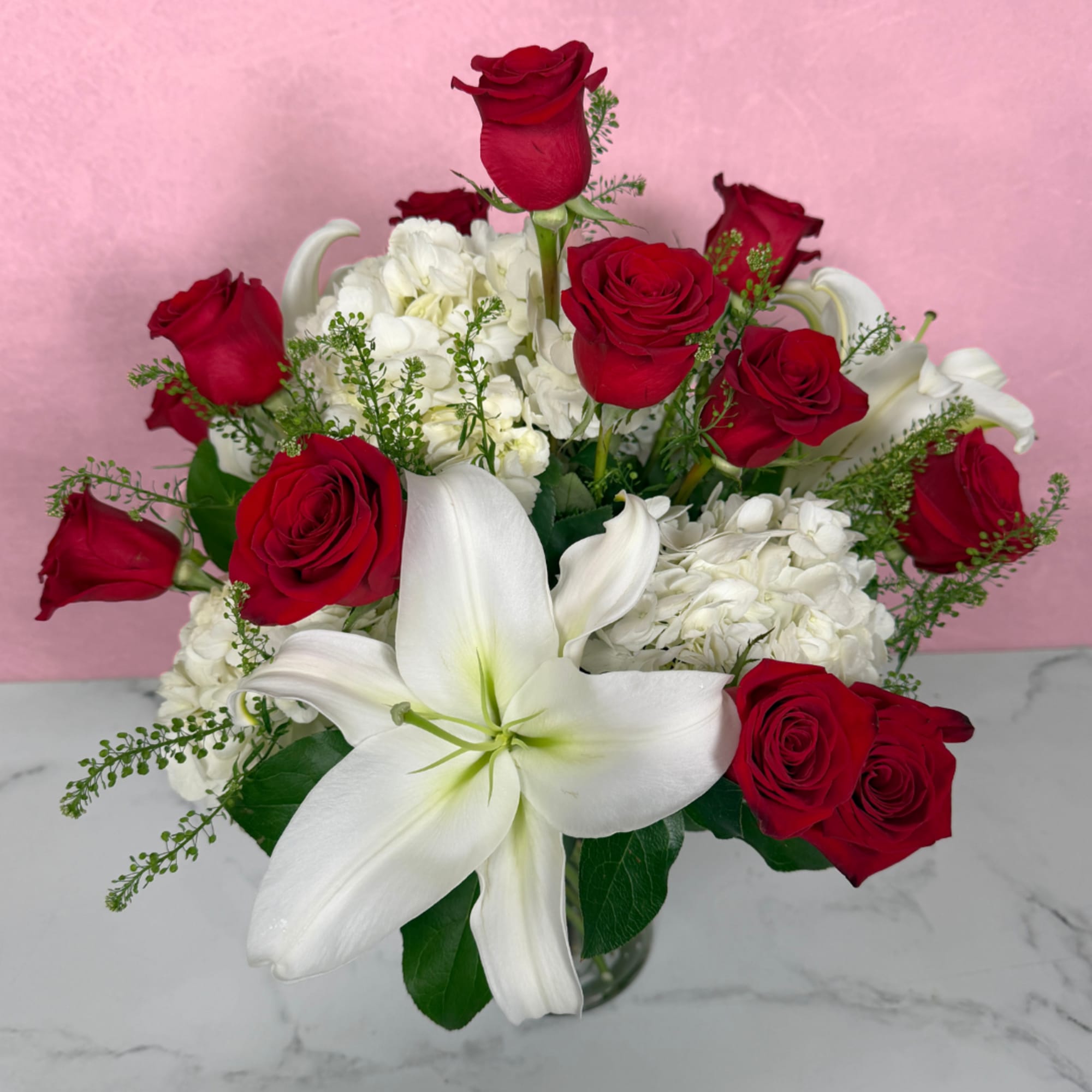Red roses and white lilies arranged in a glass vase