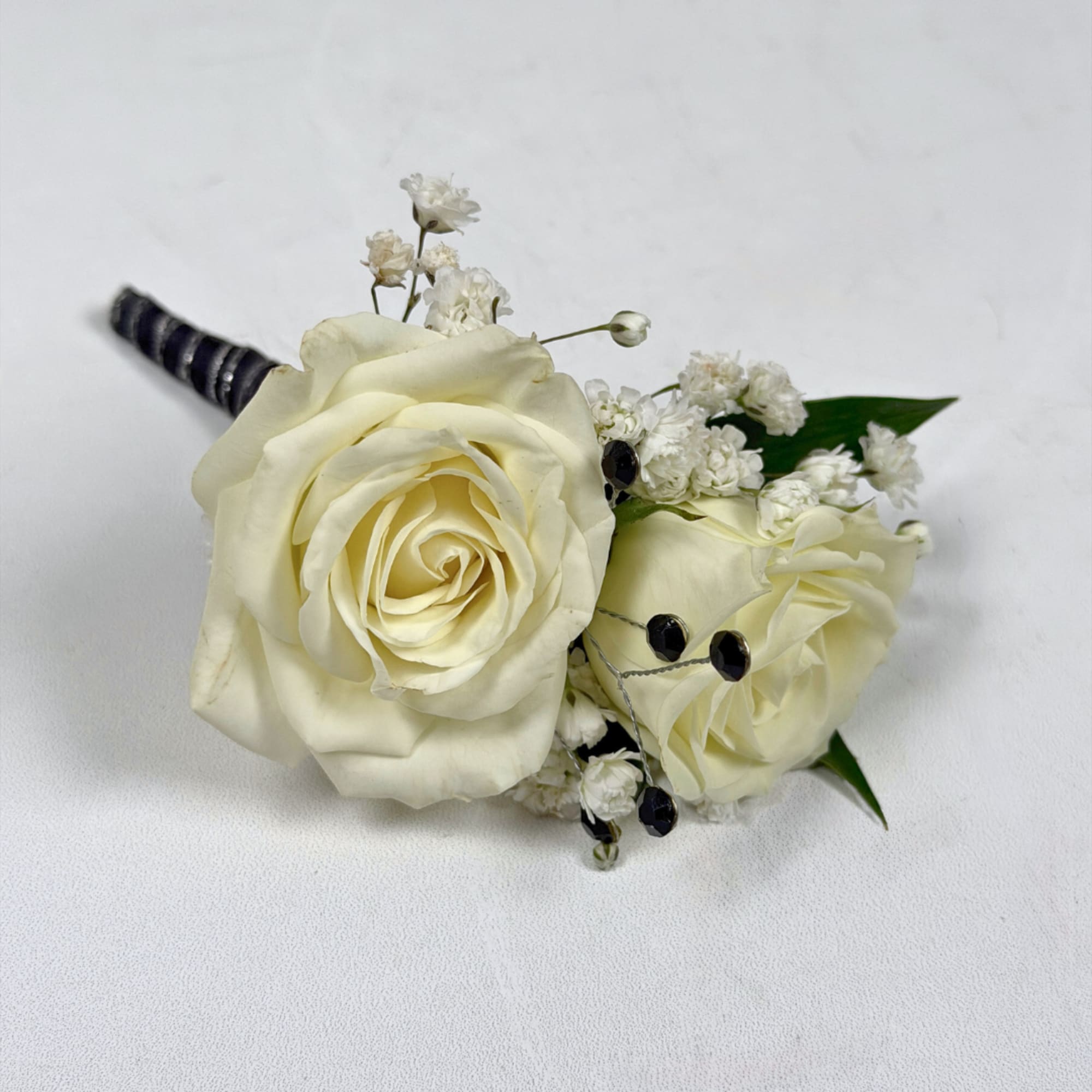 Two ivory-white roses create the refined focal point of Onyx Boutonniere, a