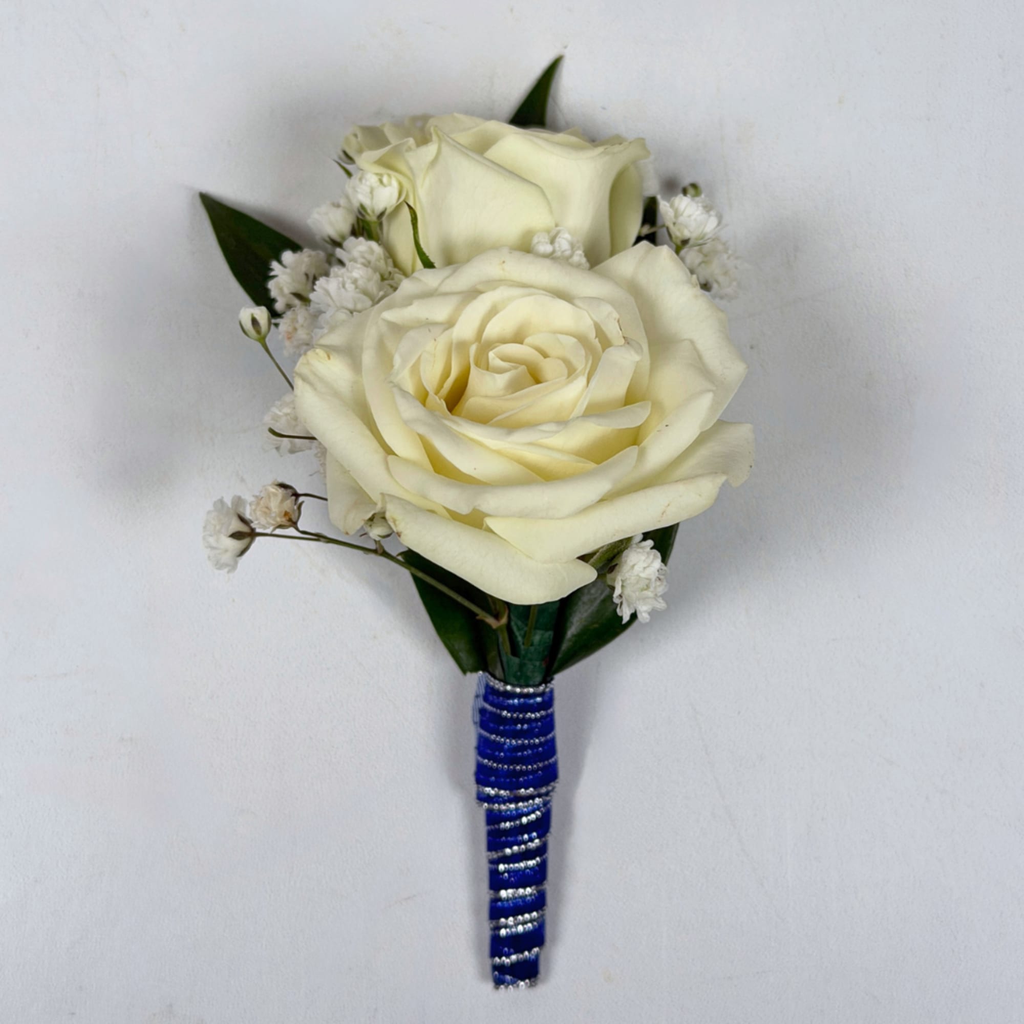 Two cream-white roses, clustered tightly with delicate white filler blooms and dark