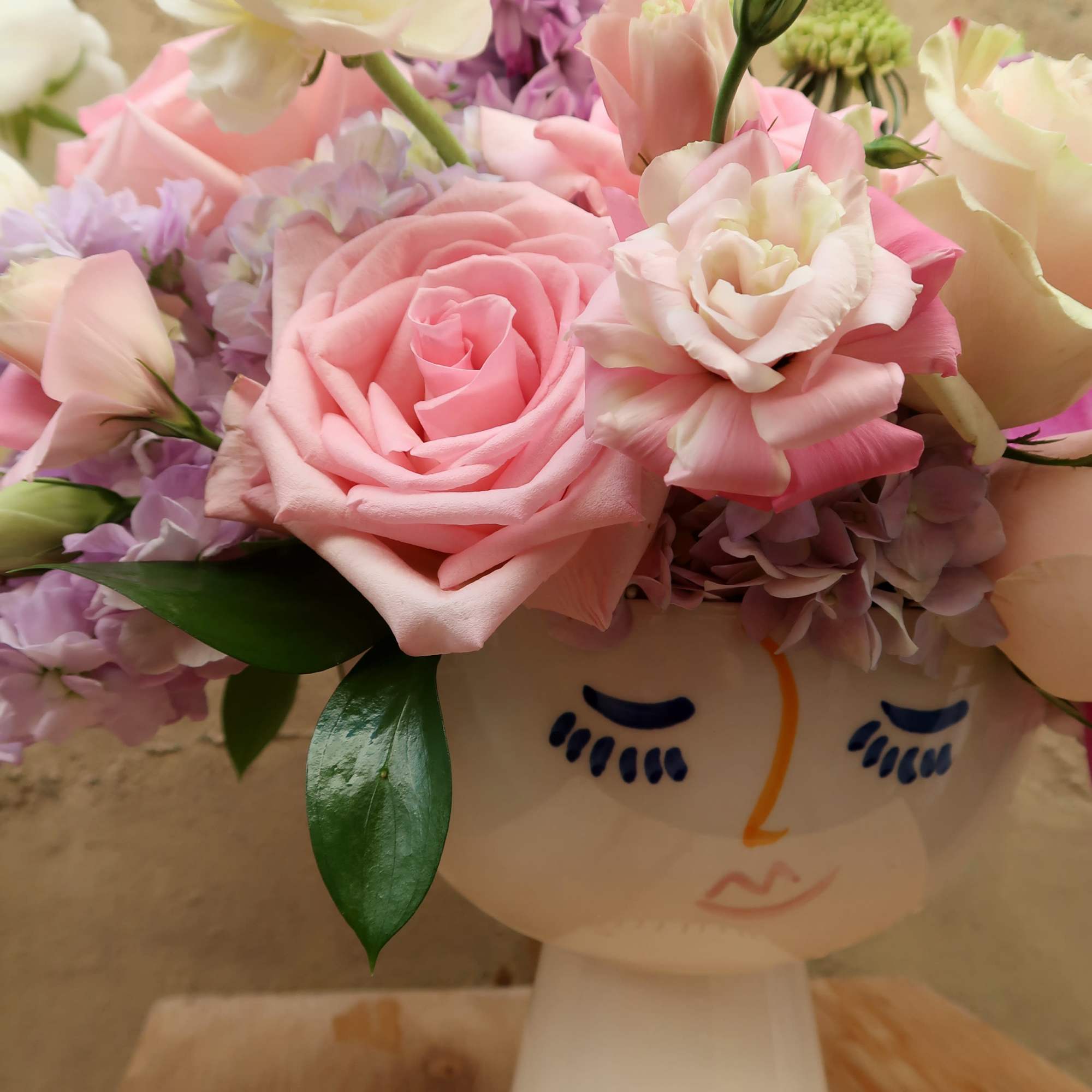 Pink and white flowers arranged in a face-shaped vase