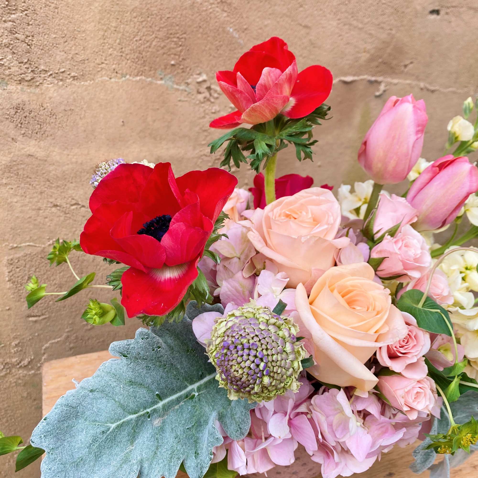 Bouquet of red anemones, pink roses, and pale tulips