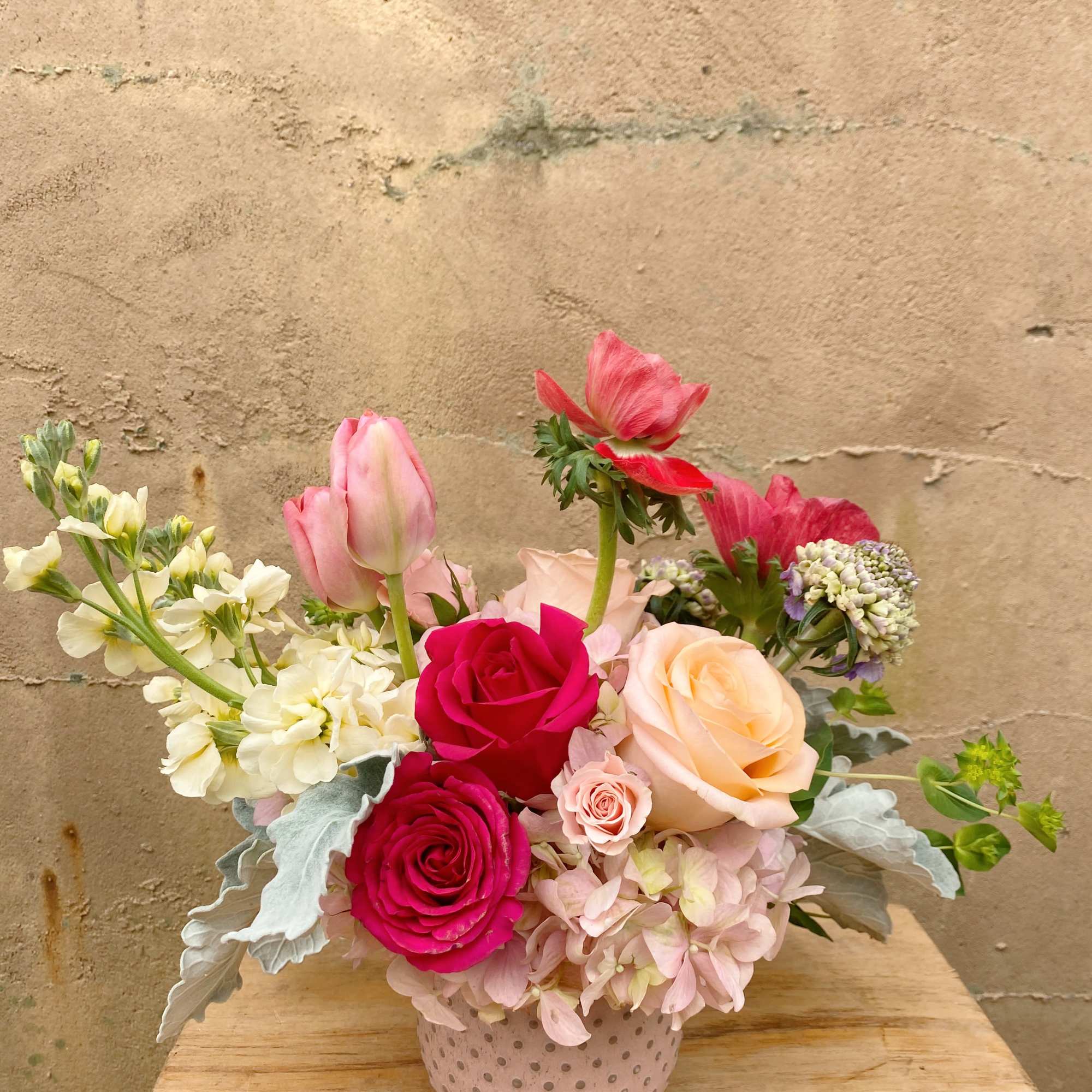 Pink and peach roses with tulips in a dotted ceramic vase