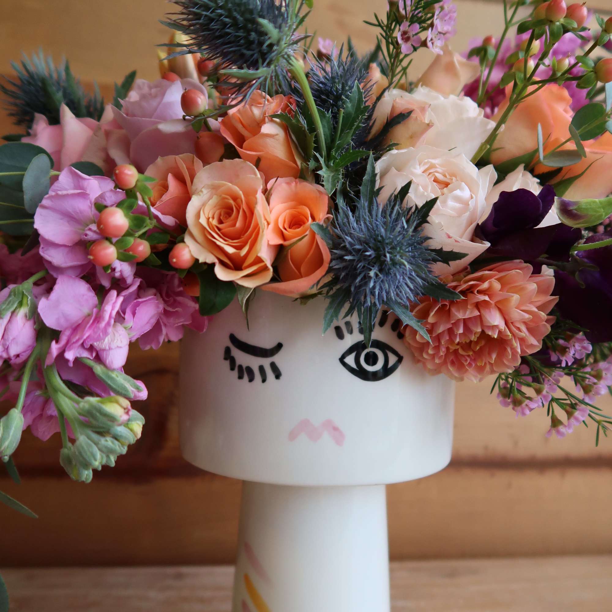 Mixed bouquet in a white face vase with peach, pink, and white blooms