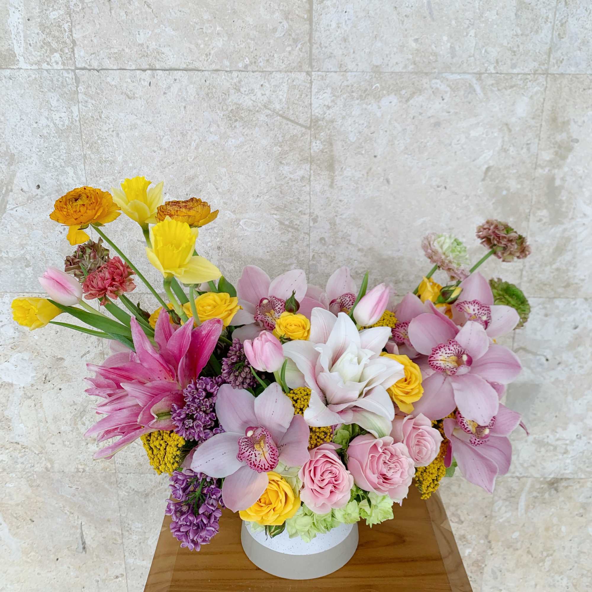 Mixed bouquet of pink, yellow, and white flowers in a round white box