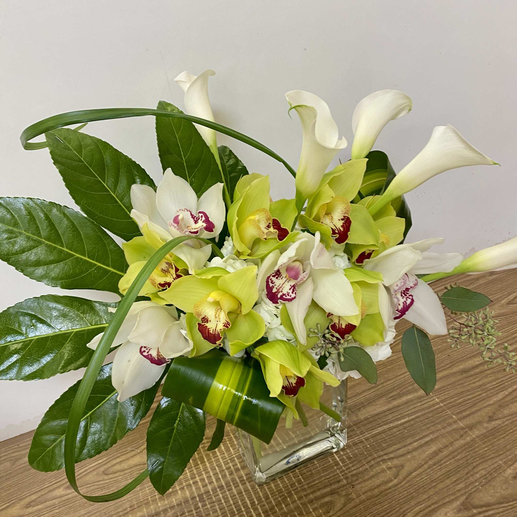 White and lime green orchids arranged in a clear square vase