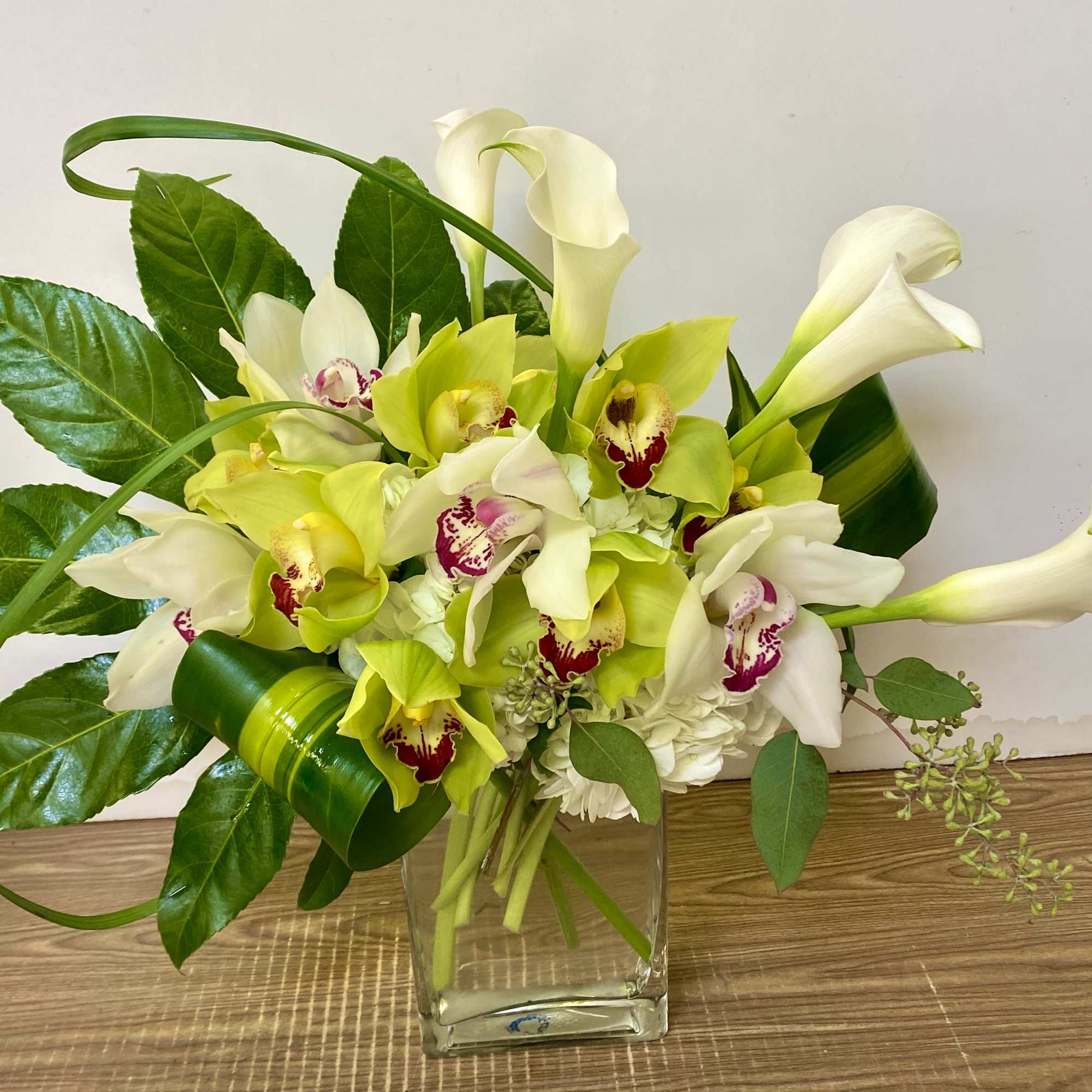 White and lime orchids arranged in a clear glass vase