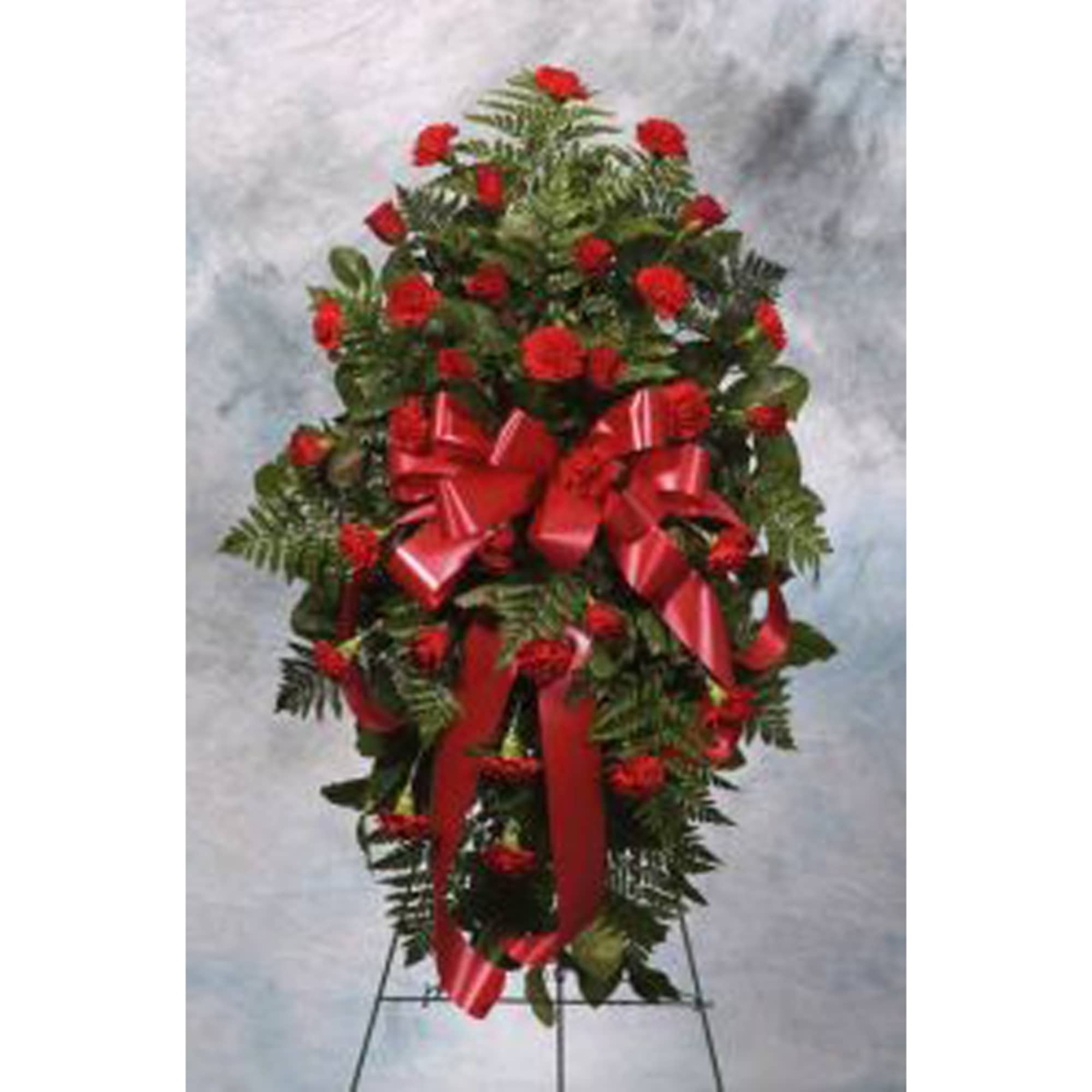 Tall standing spray with red carnations and large red bow on an easel