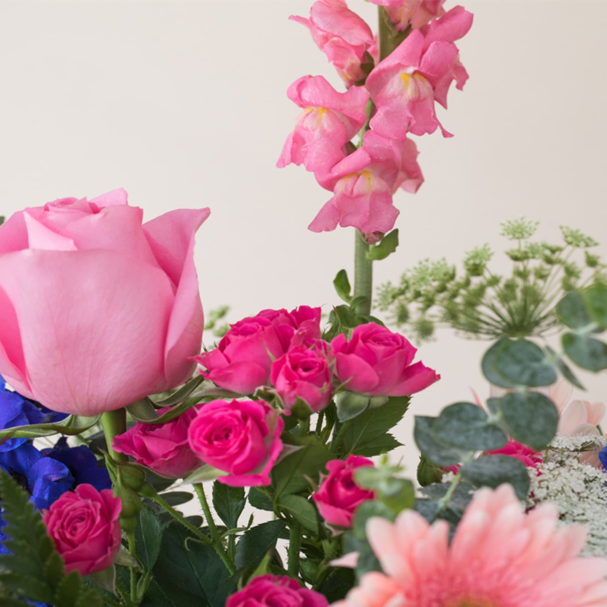 Close-up of a pink and blue mixed flower arrangement with roses and snapdragons