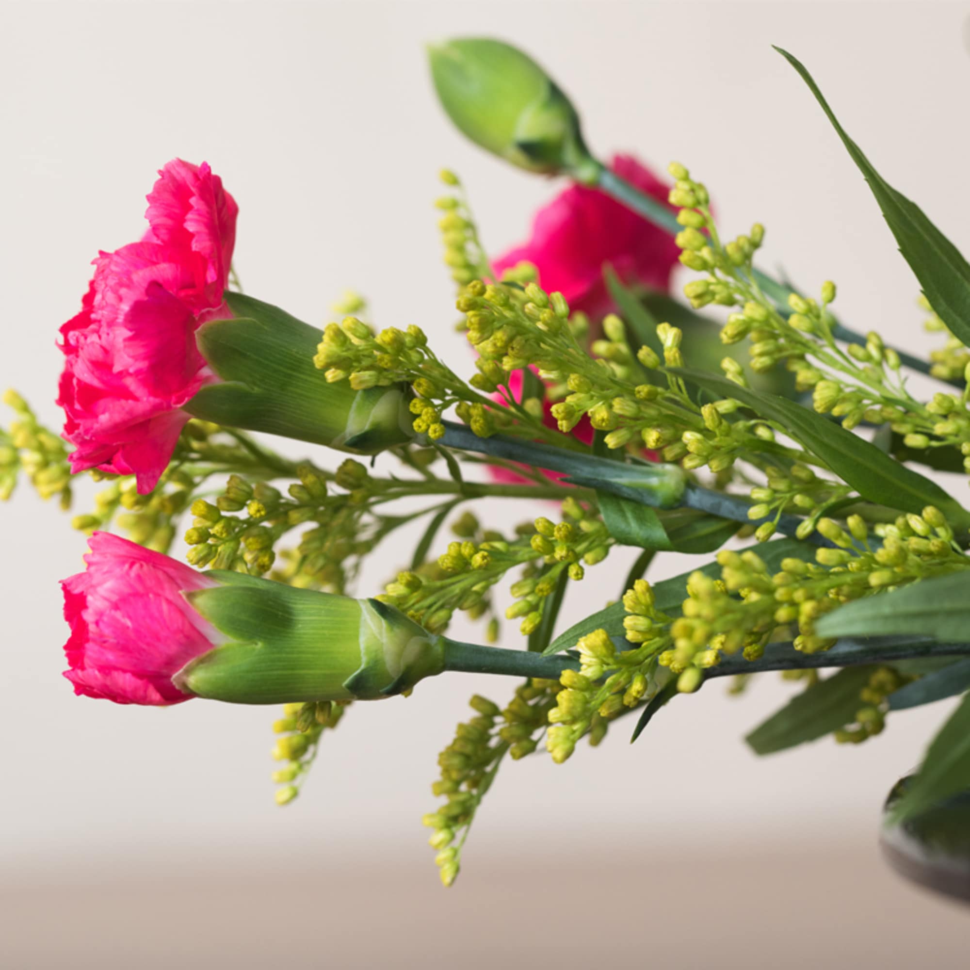 Close-up of bright pink carnations with yellow filler flowers in a bouquet